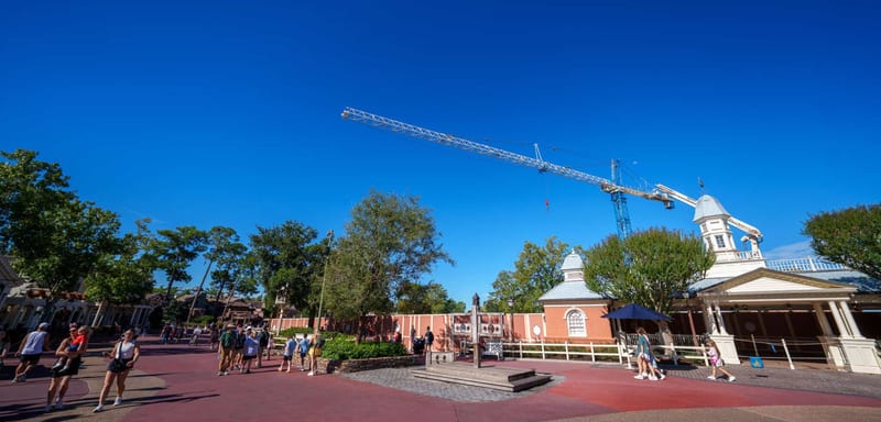 The Piston Peak Tower Crane Is Moving at Magic Kingdom, and Its Jib Appears to Reach Over a Liberty Square Walkway