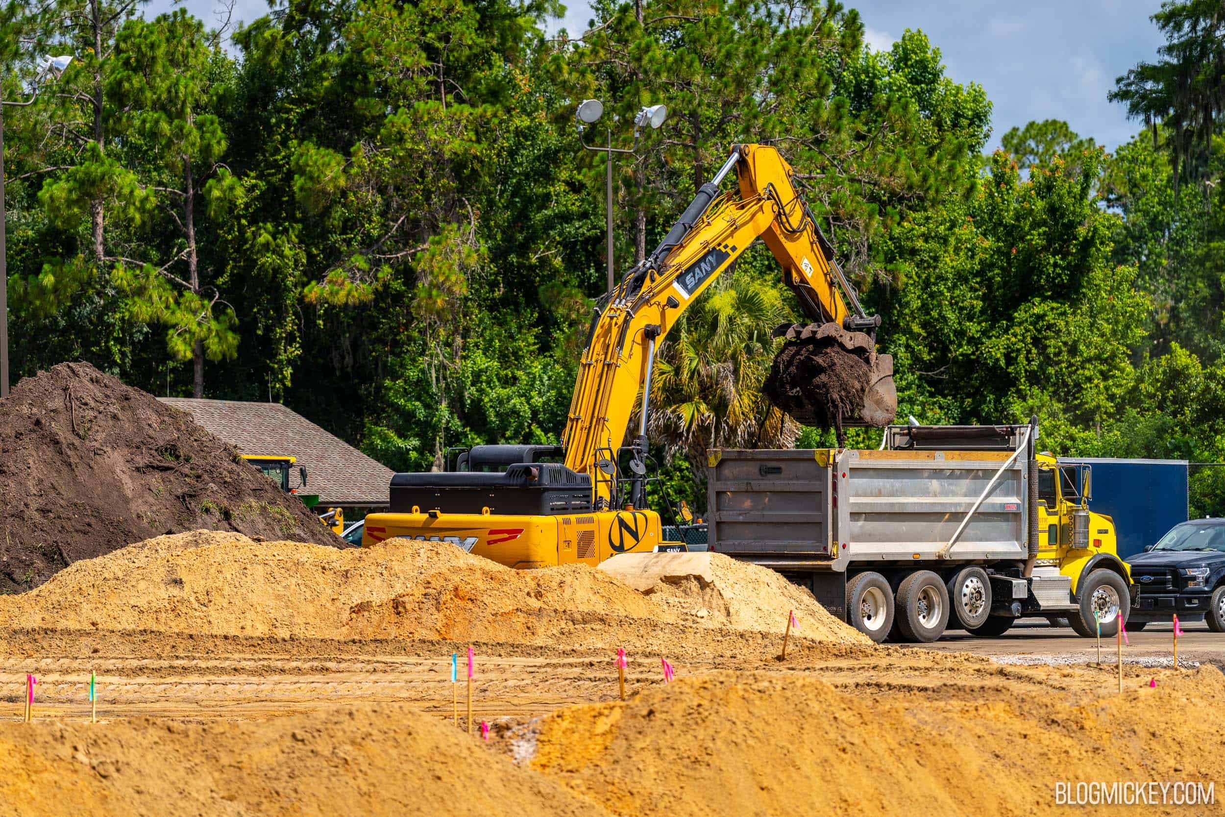 Excavators and a dump truck working on bare sand and dirt during construction of the new pool at Disney's Fort Wilderness