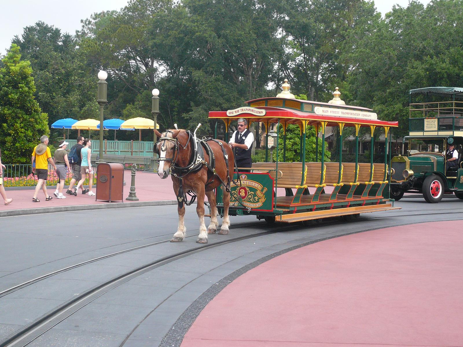A horse-drawn streetcar on Main Street at Magic Kingdom with the embedded steel rails visible in the foreground pavement