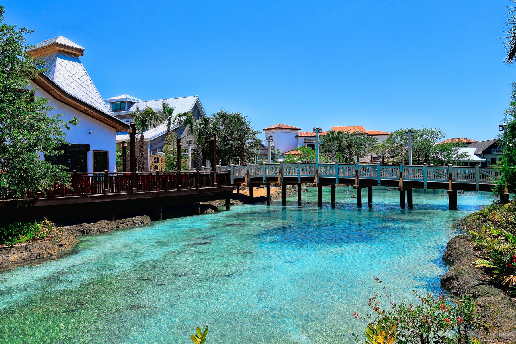 A footbridge over turquoise water at Disney Springs, with waterfront buildings behind