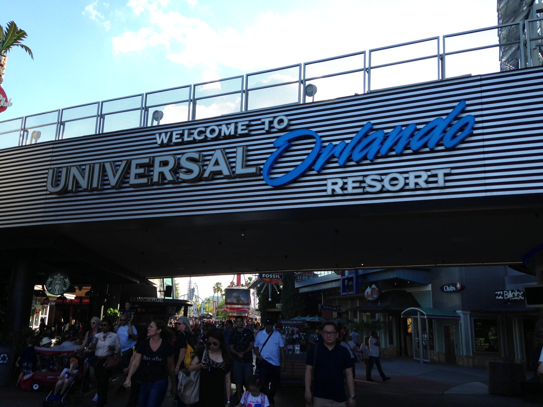 Crowds of guests walking beneath the Welcome to Universal Orlando Resort archway near CityWalk