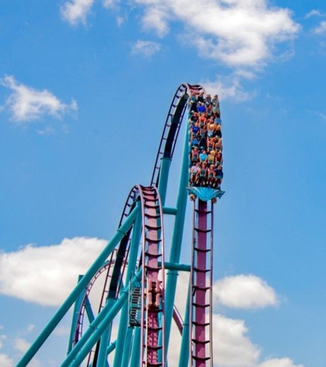 Riders crest a hill on the teal and purple Mako hypercoaster at SeaWorld Orlando