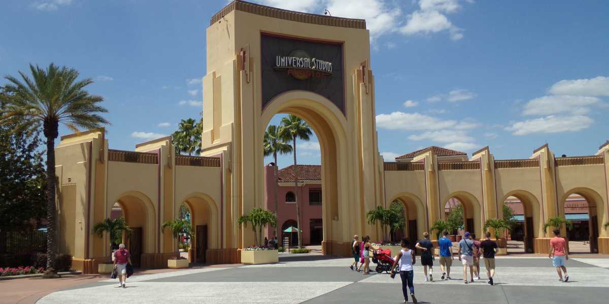 The yellow-beige entrance arches at Universal Studios Florida with guests walking through