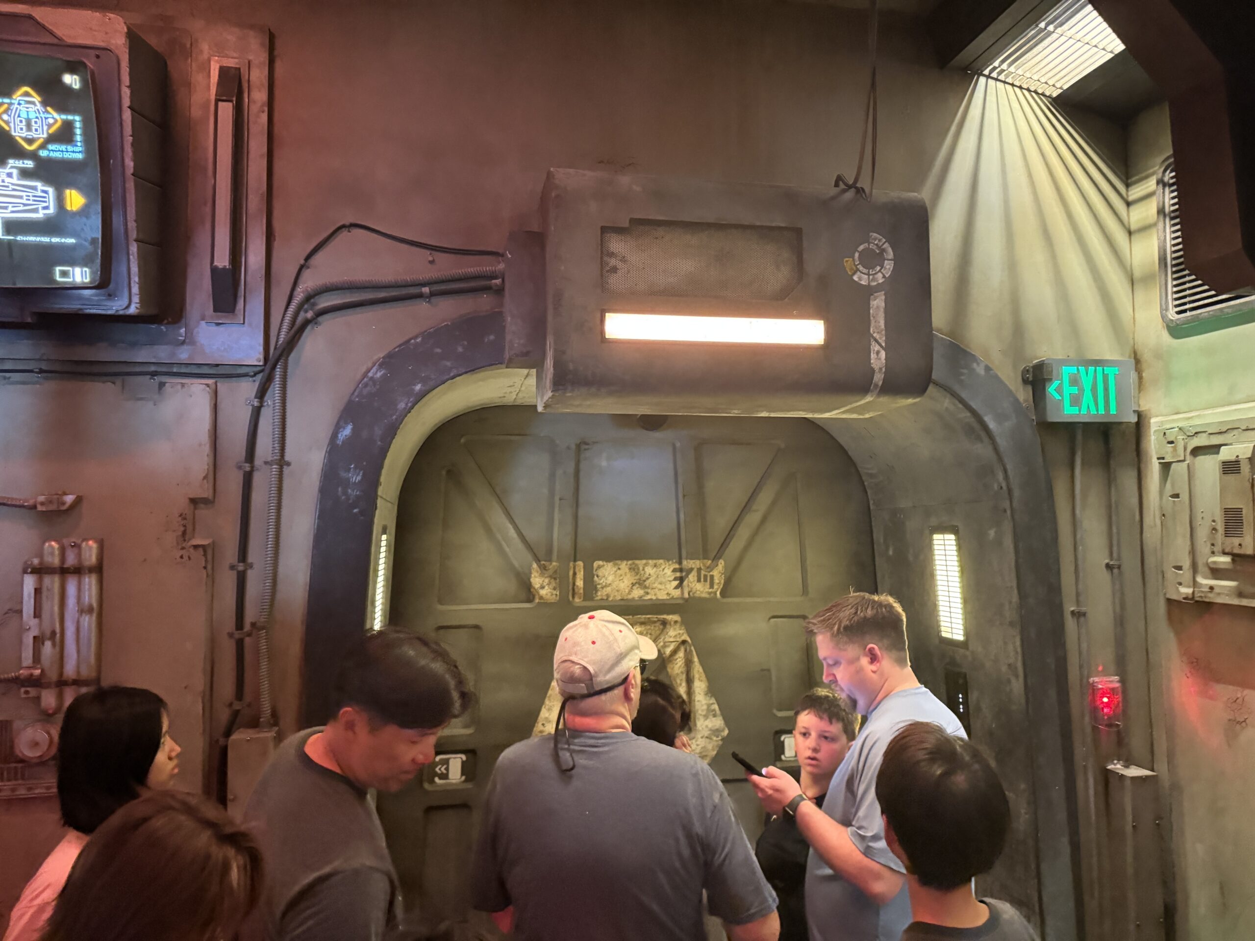 Guests standing at the sliding blast doors in the Smugglers Run queue, next to an illuminated Exit sign