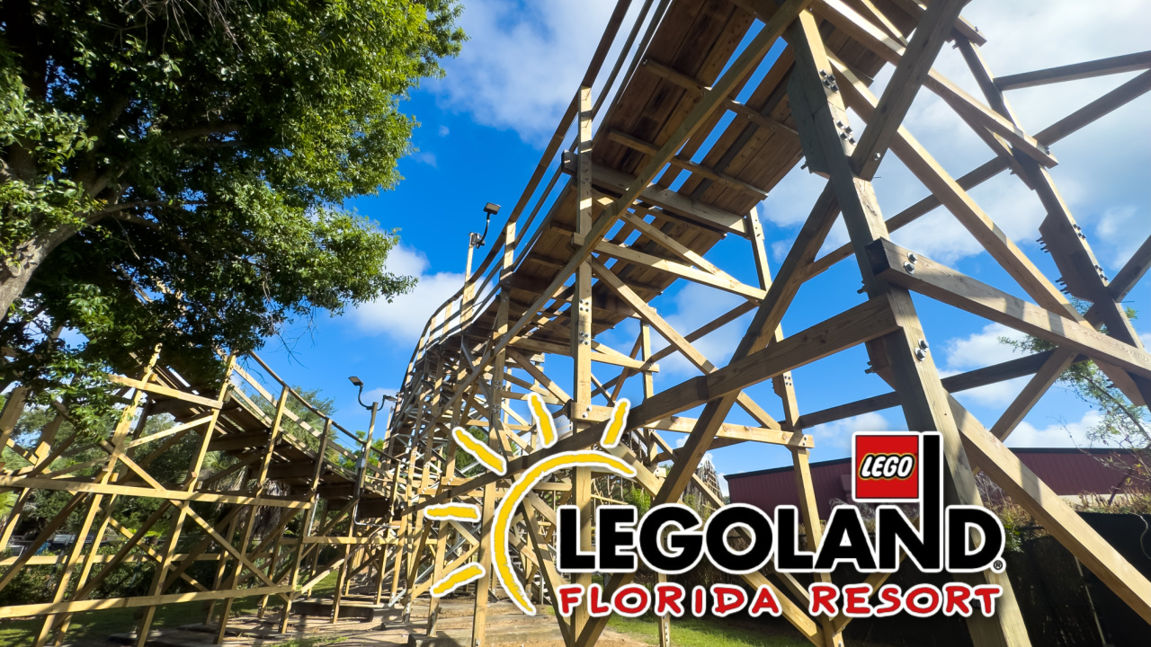 A wooden roller coaster structure built from fresh pale lumber curving against a blue sky, with a Legoland Florida Resort logo overlaid