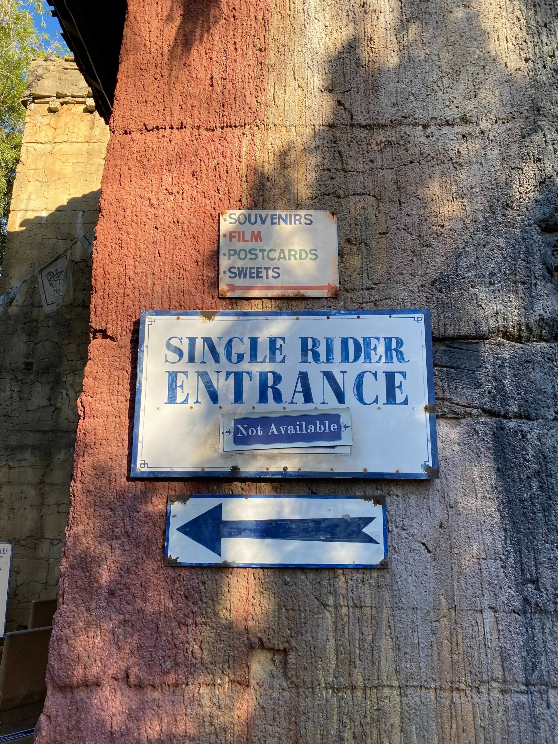 The same Single Rider Entrance sign in place on the rock wall, with the placard beneath it reading Not Available