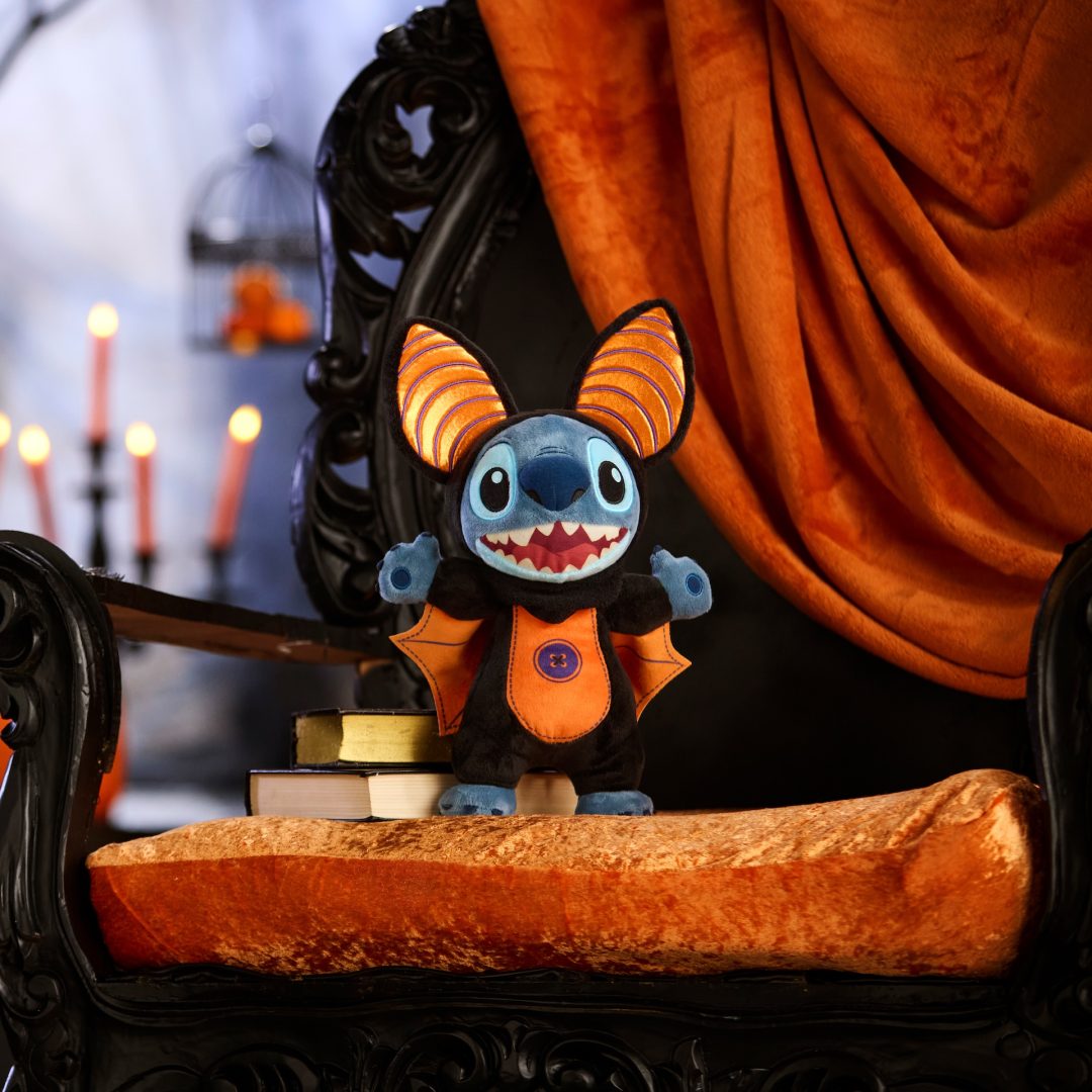 Stitch plush dressed as a vampire with an orange winged cape and striped ears