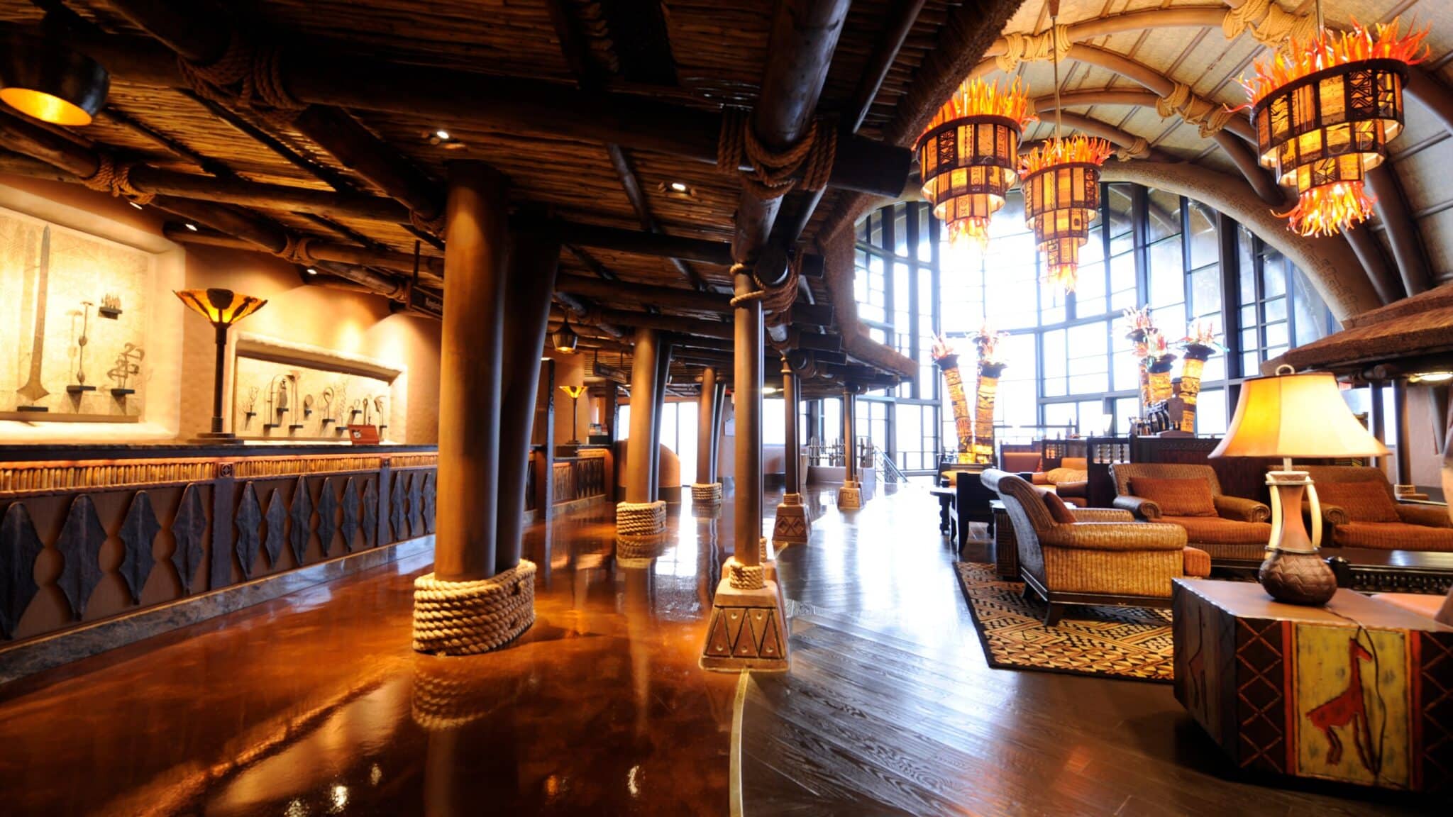 The lobby at Disney's Animal Kingdom Villas - Kidani Village, with rope-wrapped columns, hanging lantern chandeliers and a thatched arched ceiling over a wall of tall windows