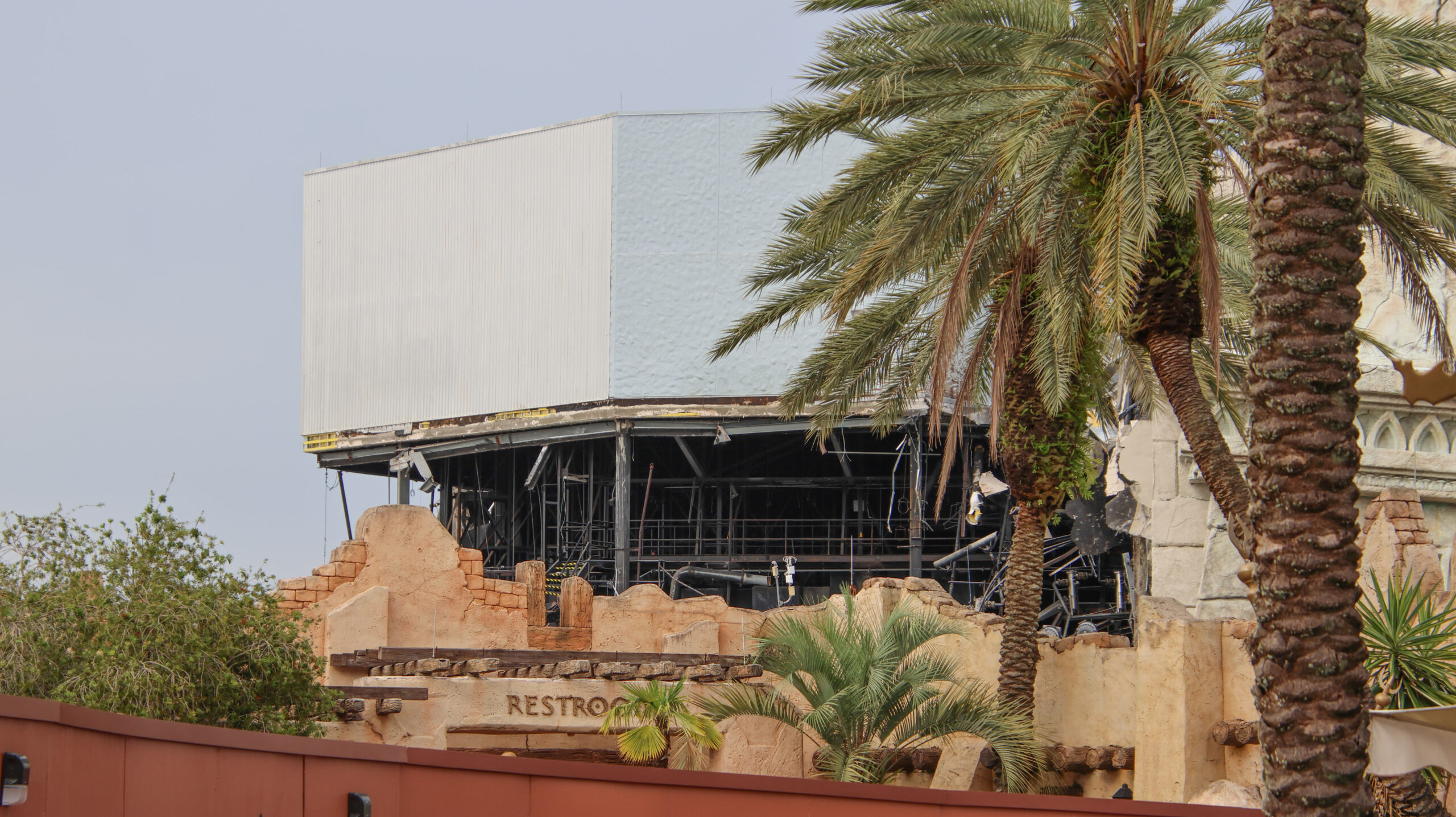 The Poseidon's Fury show building with its exterior wall removed, revealing black steel framing inside, seen over the rockwork of The Lost Continent.