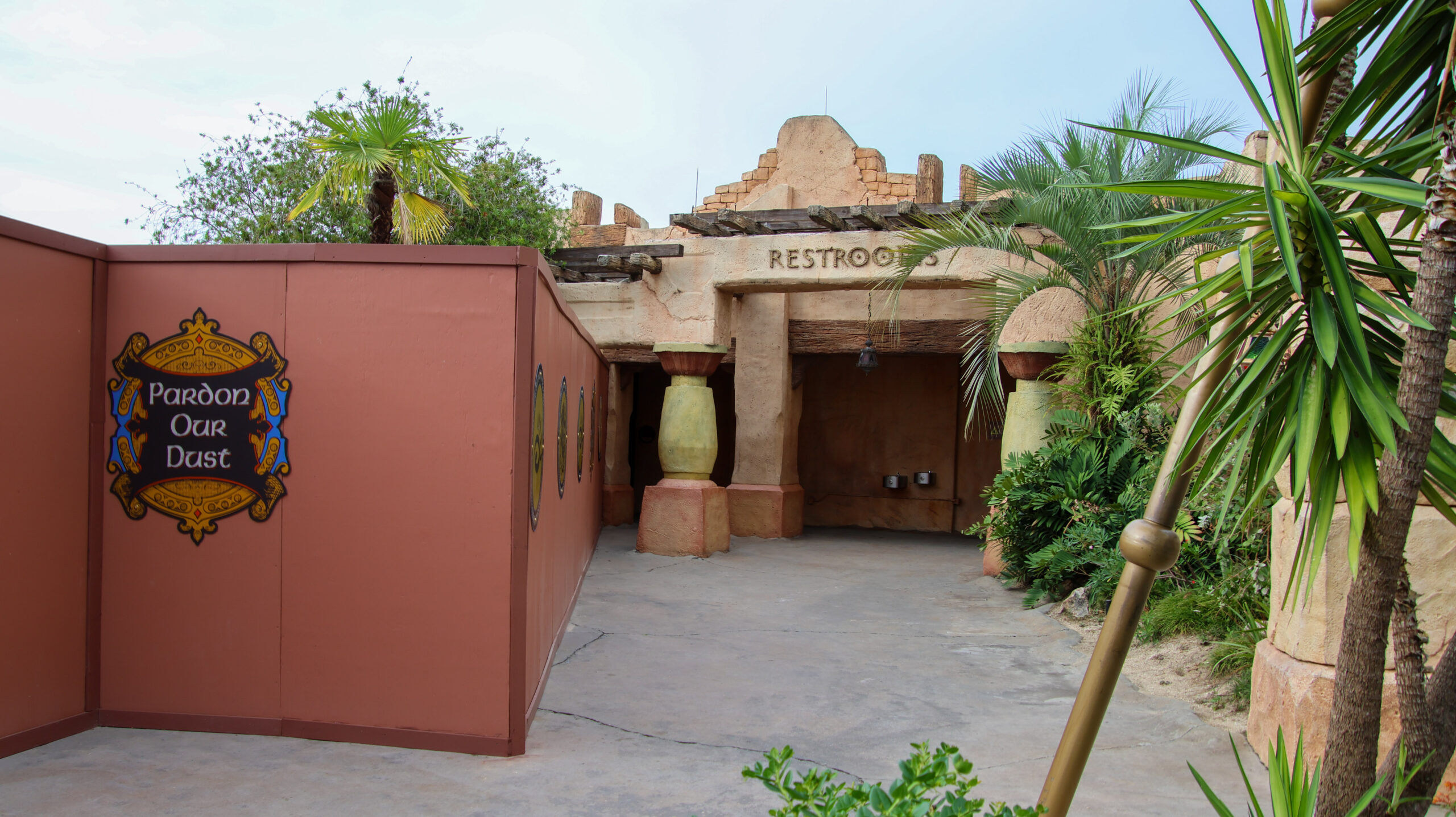 The open entrance to The Lost Continent restrooms beside a red construction wall marked Pardon Our Dust.