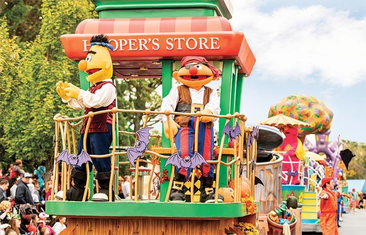 Sesame Street characters in costume wave from a parade float at SeaWorld Orlando
