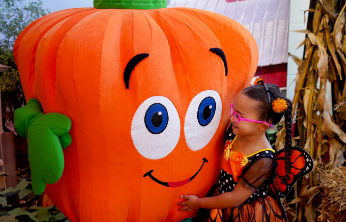 A young child in costume meets a friendly pumpkin character at SeaWorld Orlando's Halloween Spooktacular