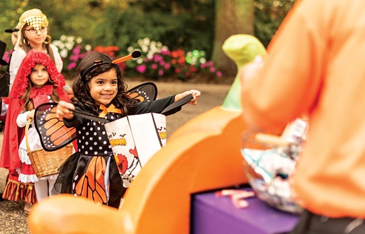 Children in Halloween costumes collect candy at a pumpkin-decorated station on SeaWorld Orlando's trick-or-treat trail