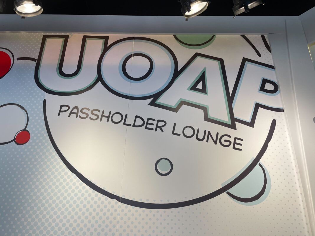 A comic-book style wall mural reading UOAP Passholder Lounge, lit by ceiling spotlights