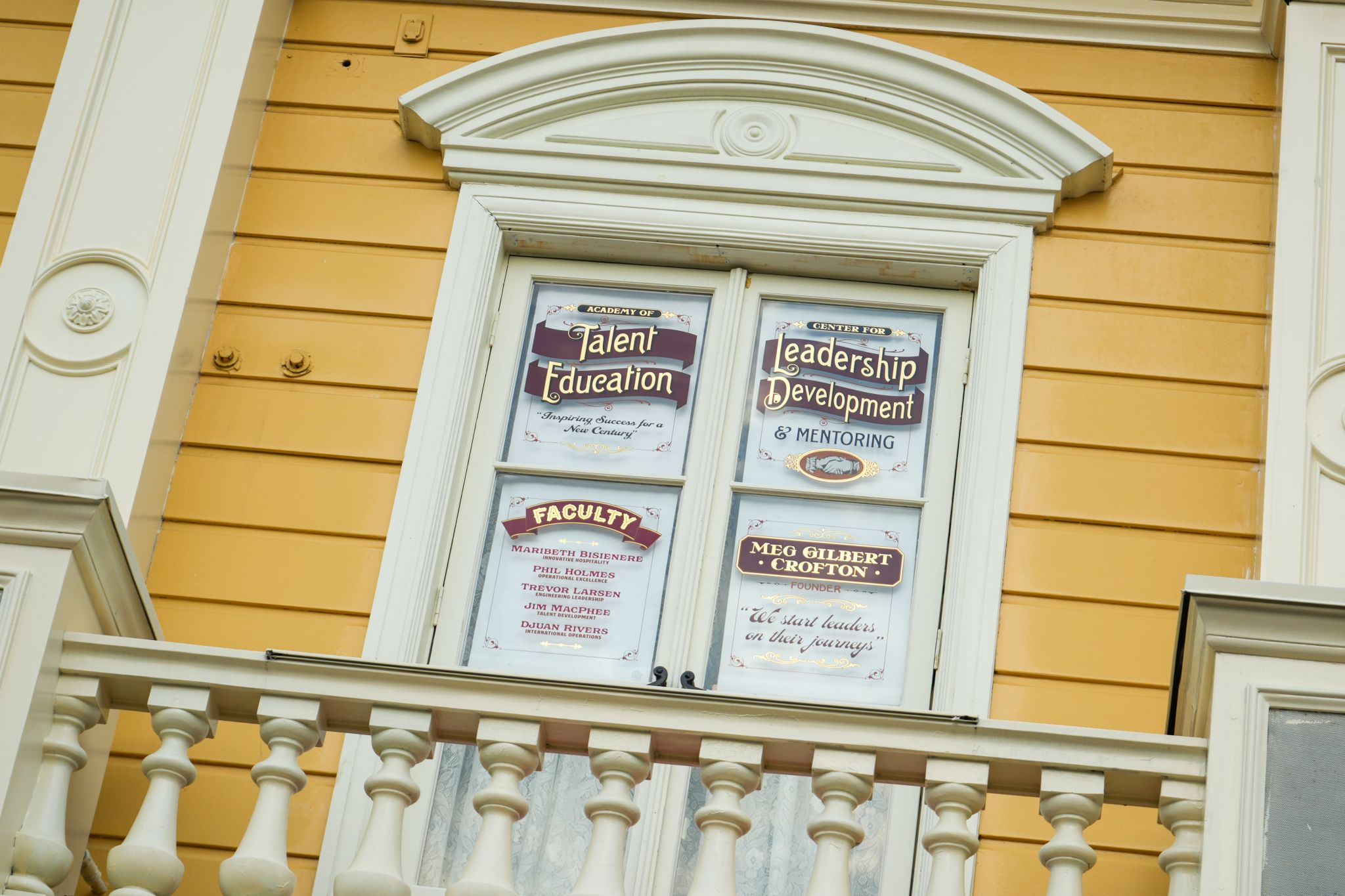 A second-floor Main Street, U.S.A. window with two painted panels, one reading Academy of Talent Education and listing a faculty of five Disney executives, the other reading Center for Leadership Development and Mentoring for Meg Gilbert Crofton