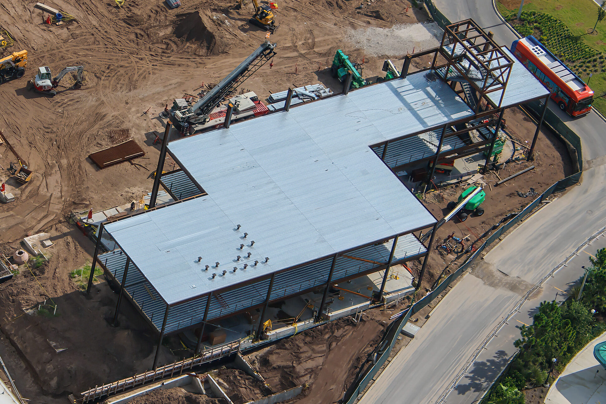 Close aerial view of the metal roof decking on the Epic Universe multipurpose building, with a tall box-shaped steel framework rising above the deck near one end