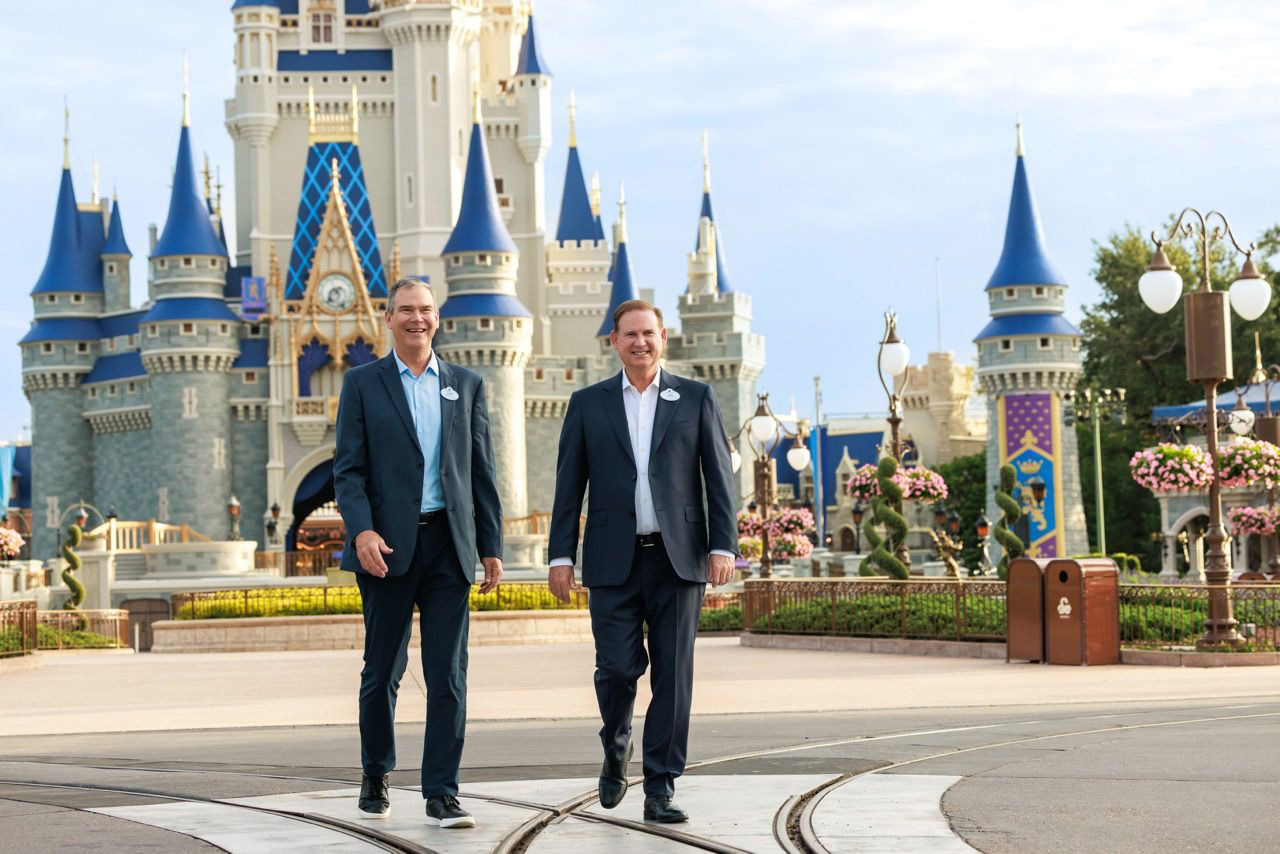 Jeff Vahle and Joe Schott walking side by side down Main Street, U.S.A. with Cinderella Castle behind them, both wearing Disney cast name tags