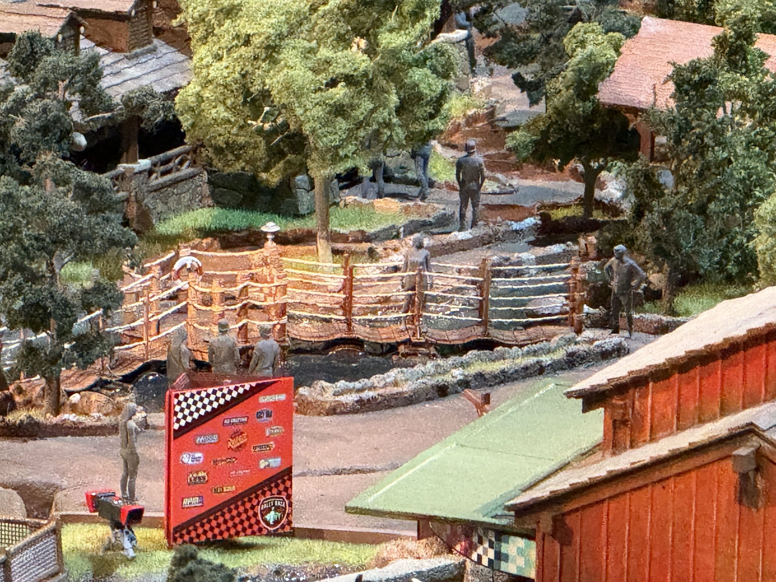 A zigzagging timber plank walkway with rope railings crossing a rocky creek bed in the model, with guest figures on and around it