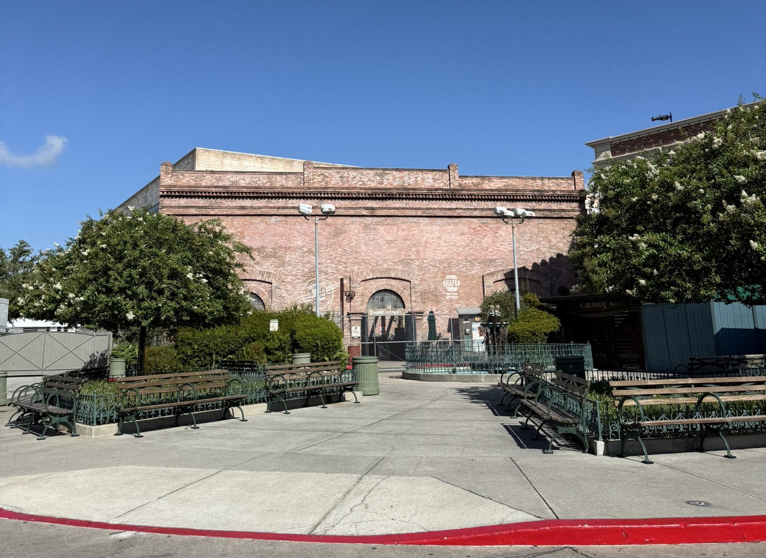 The brick facade of the former Fast and Furious Supercharged building with no attraction name on it, benches empty in the foreground and a NAPA logo still painted on the brick near the entrance