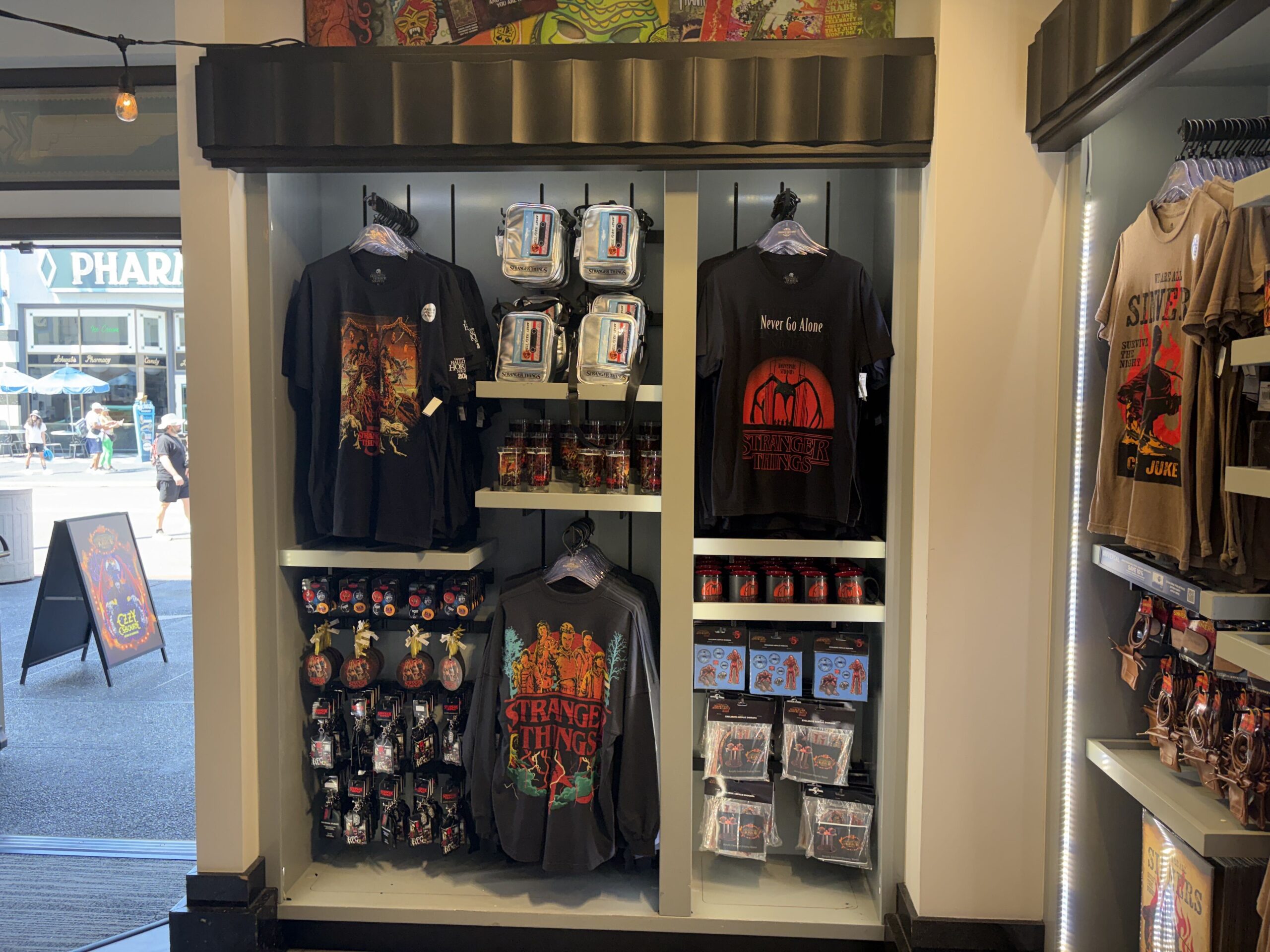 In-store display bay holding Stranger Things tees, silver cassette purses, glasses, mugs, ornaments and acrylic dioramas