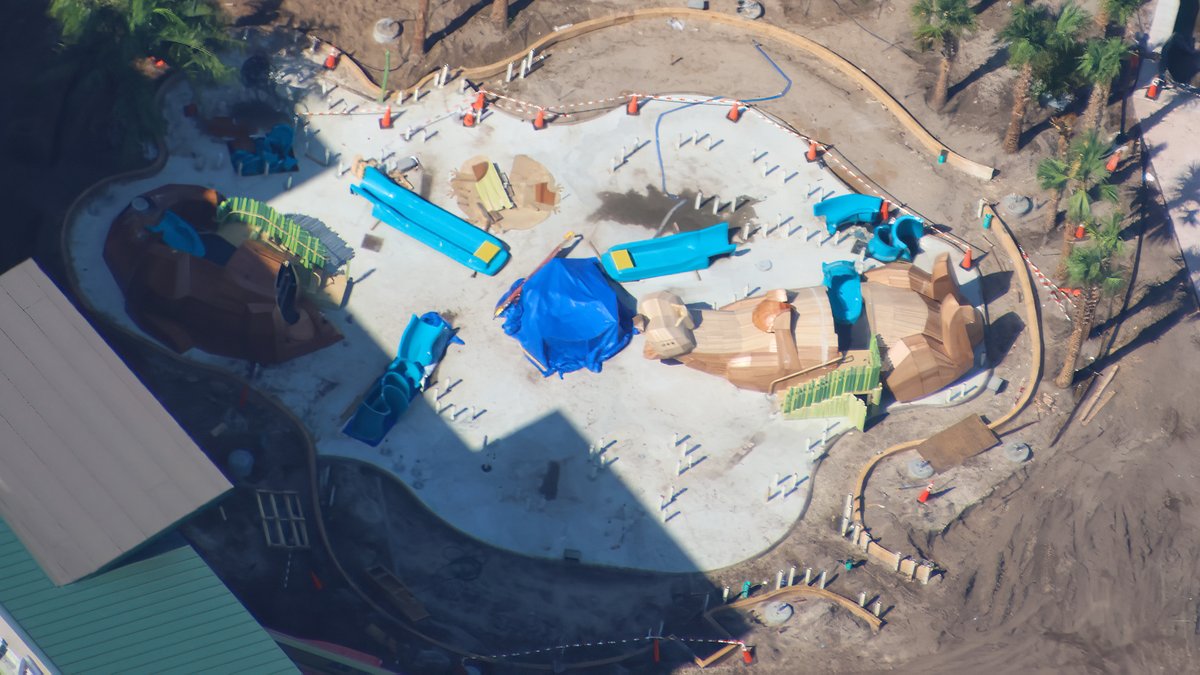 Overhead view of the Otter Springs splash pad with a large wood-style otter figure, turquoise slides and orange safety fencing