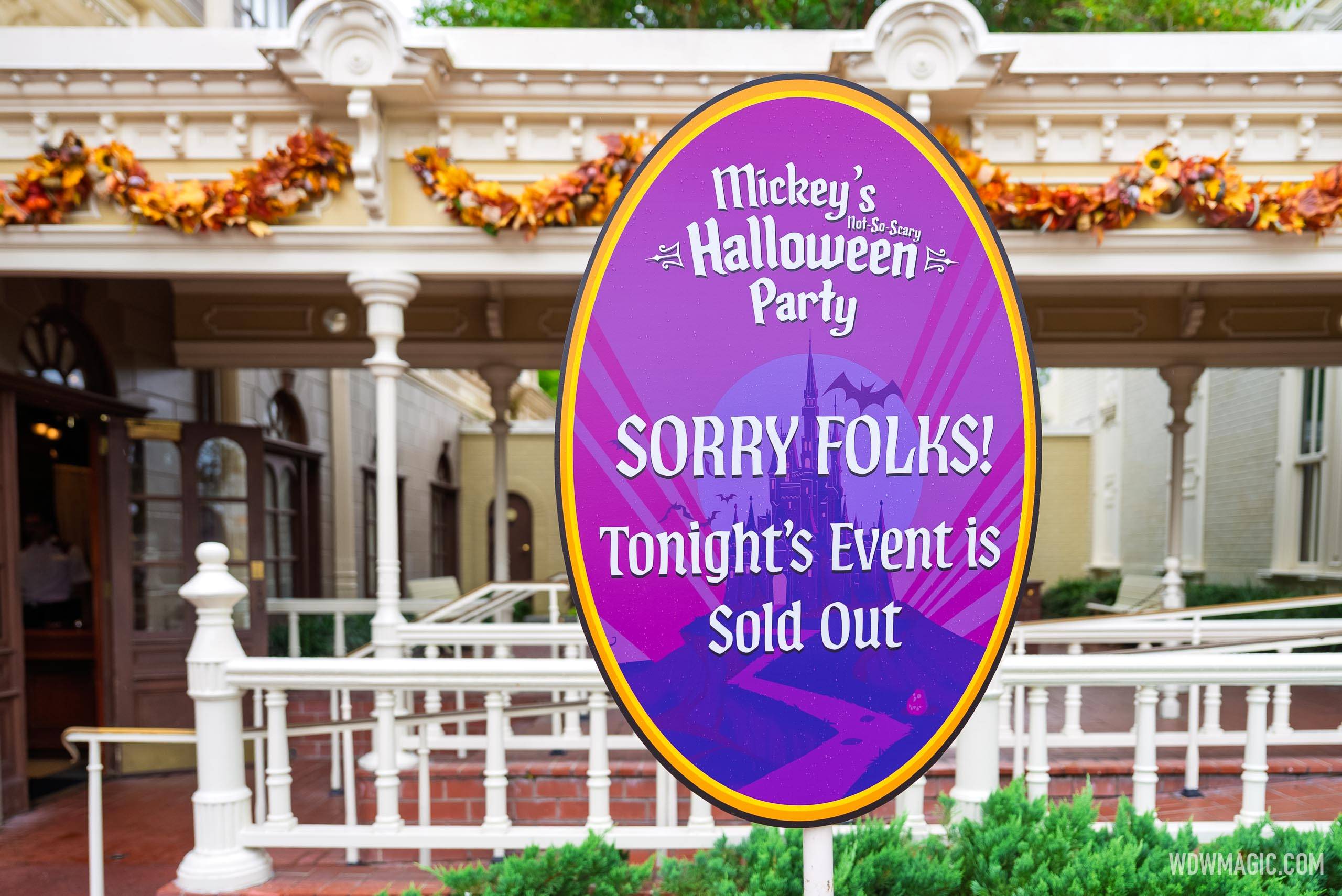 An oval purple sign on a white post outside a Main Street building reads Sorry Folks, Tonight's Event is Sold Out, under the Mickey's Not-So-Scary Halloween Party logo