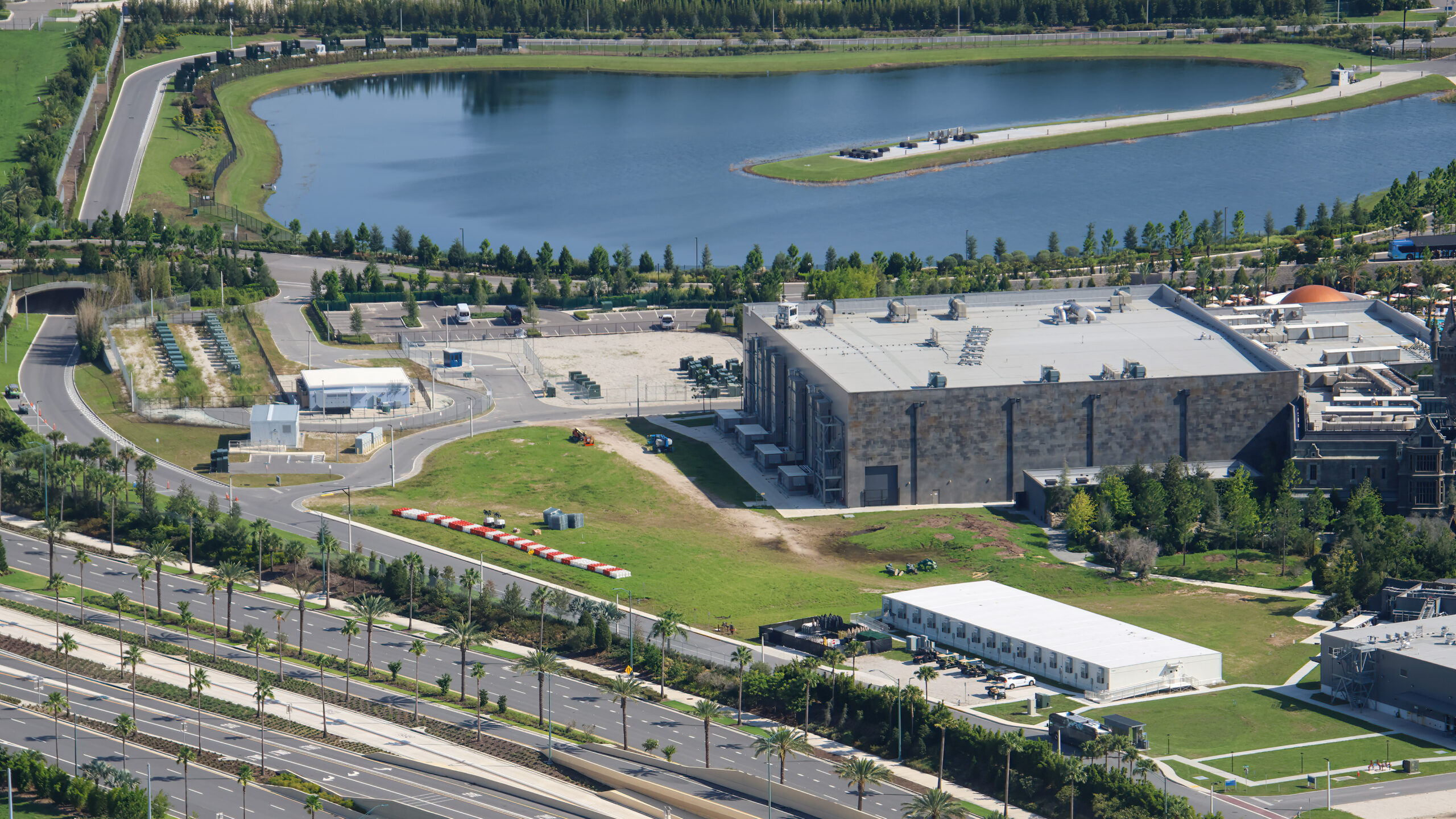 Aerial looking across the back of Dark Universe with a retention pond, the stone show building and construction barriers staged on the grass