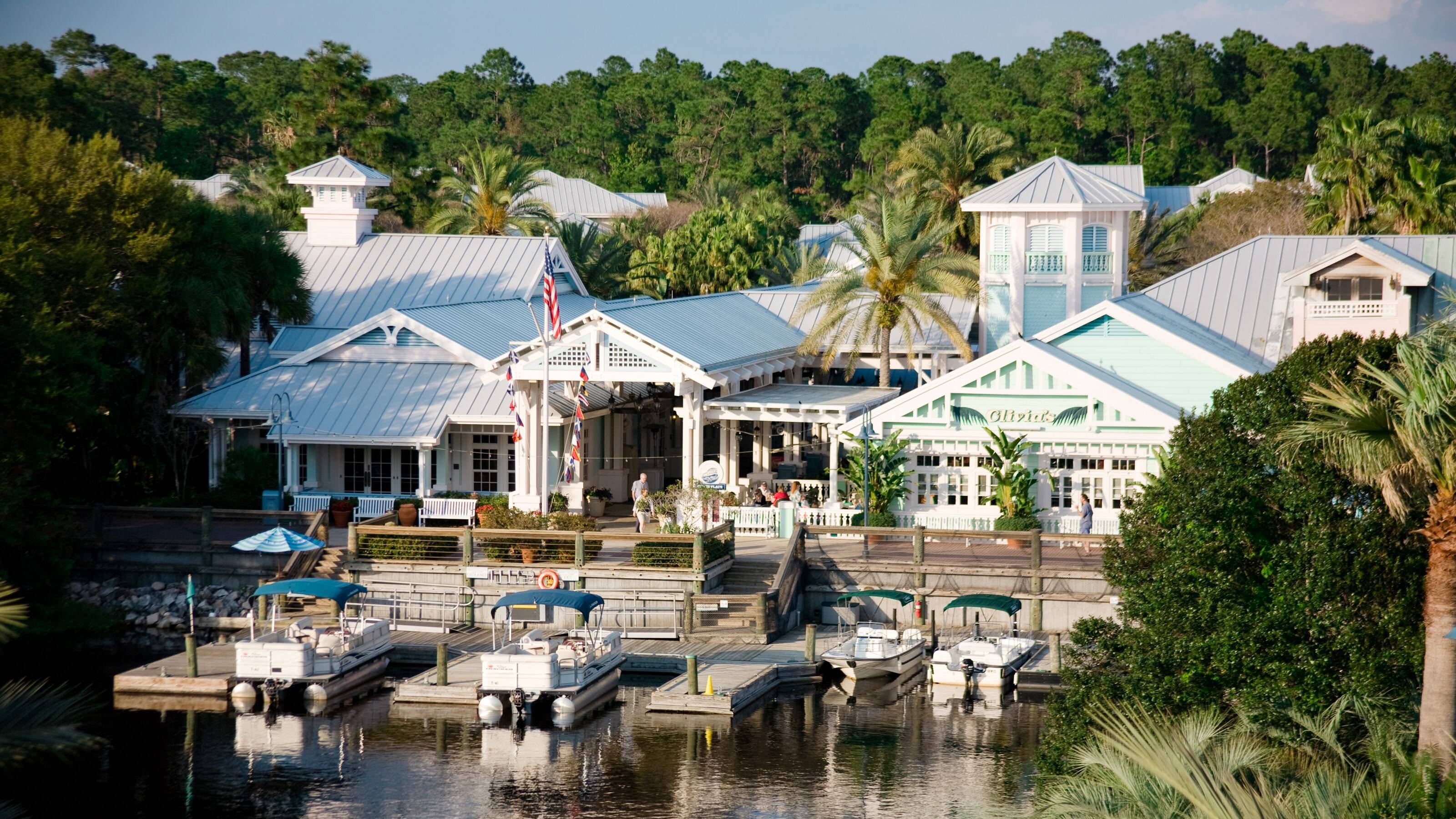 Old Key West Resort's Hospitality House seen from across the water, with the mint green Olivia's building and boats at the marina dock