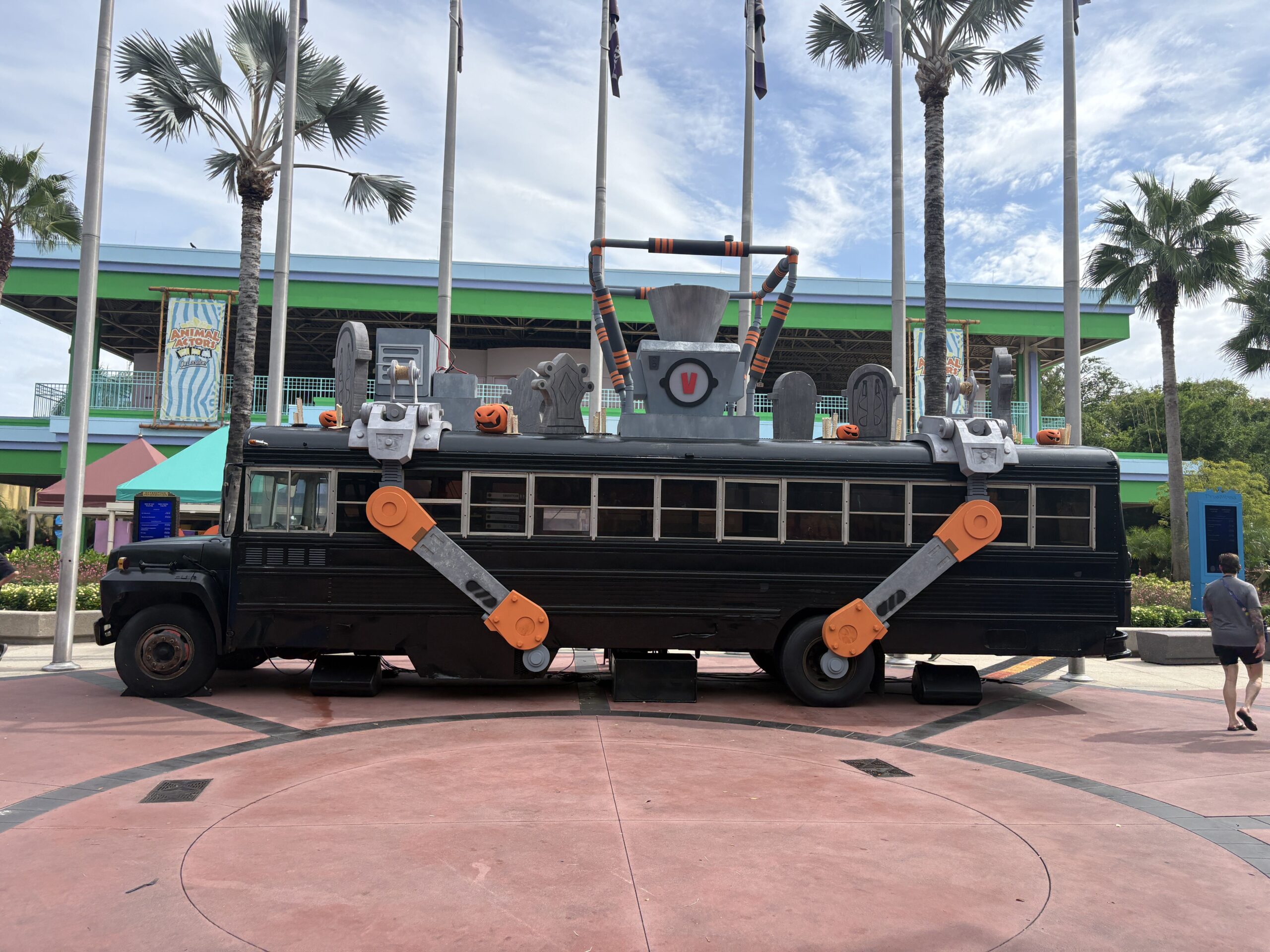 Full side profile of the black Battle Bus showing its roof rig of tombstones, pumpkins, a grey hopper and the housing beneath it stamped with a red V