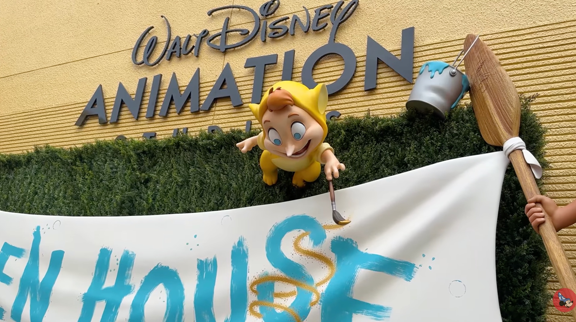 A yellow-hooded Lost Boy figure leans over a white banner reading Open House, holding a paintbrush that has drawn a gold swirl around the letter S