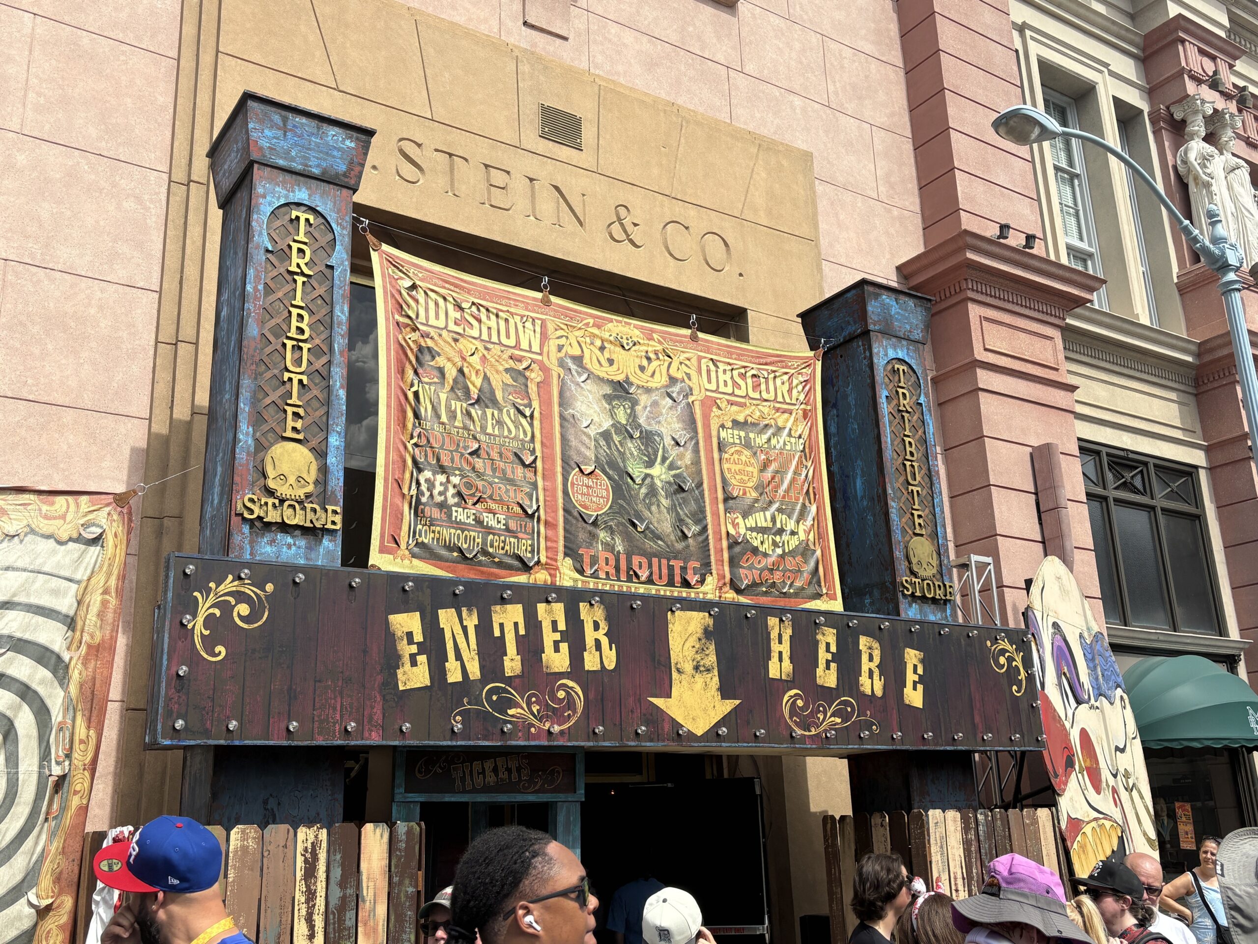 The Tribute Store facade at Universal Studios Florida with a Sideshow Obscura banner and a wooden marquee reading Enter Here