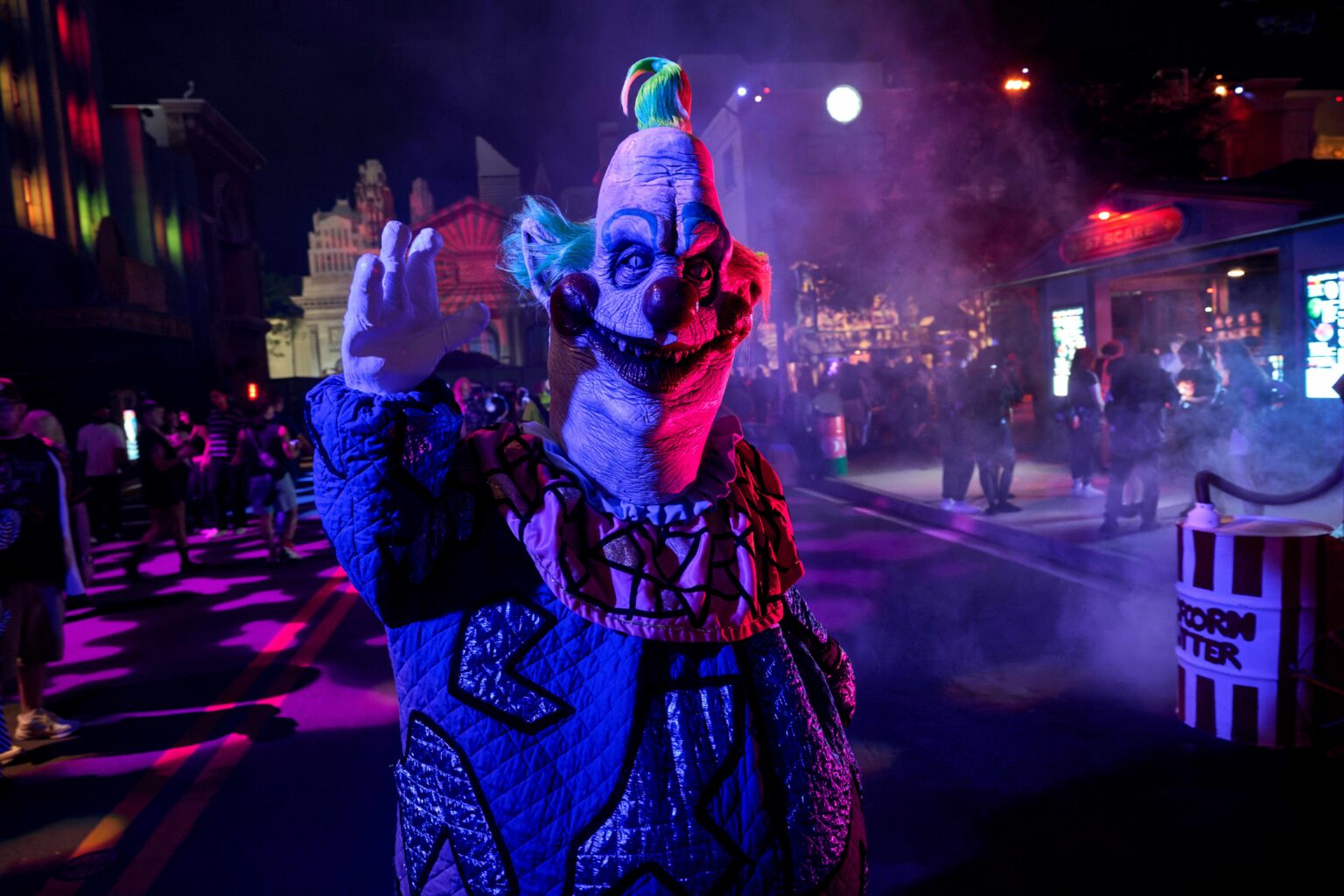 A Killer Klown from Outer Space in a blue and silver costume on a fog-covered street at Halloween Horror Nights 35