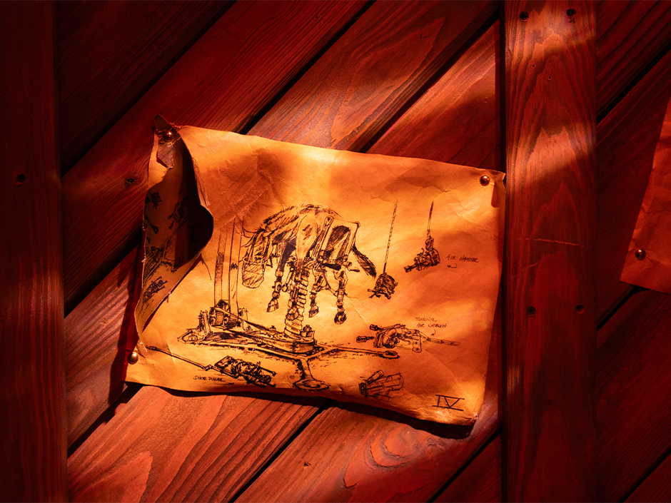 A curling sheet of aged paper pinned to a red lit wood plank wall, carrying an ink drawing of a horse standing in a mechanical shoeing rig, with handwritten callouts reading AIR HAMMER, TORQUE AIR WRENCH and SHOE PULLER and the numeral IV in the lower right corner.