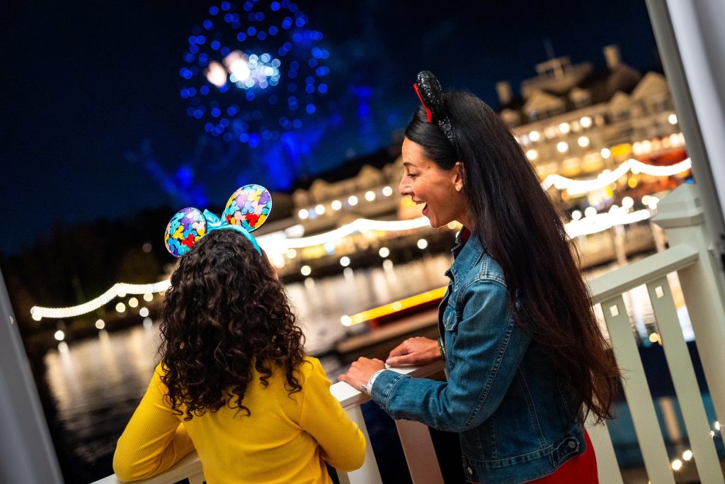 Guests watching fireworks from a Walt Disney World deluxe resort balcony at night