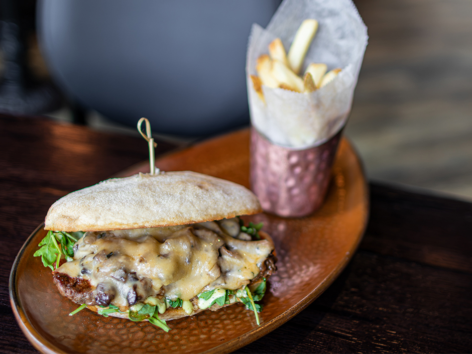 A grilled steak sandwich on a French baguette with caramelized onions, roasted mushrooms and arugula