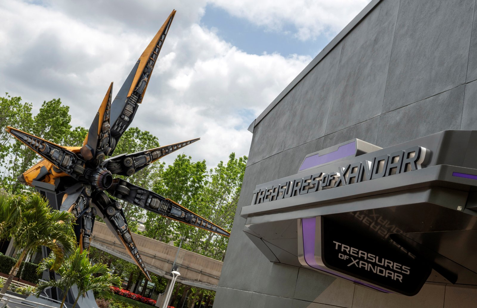 The Treasures of Xandar sign on a gray building beside the orange and black starblaster sculpture at EPCOT