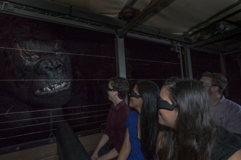 Riders wearing 3D glasses sit in an expedition vehicle beside the giant, snarling face of the King Kong animatronic