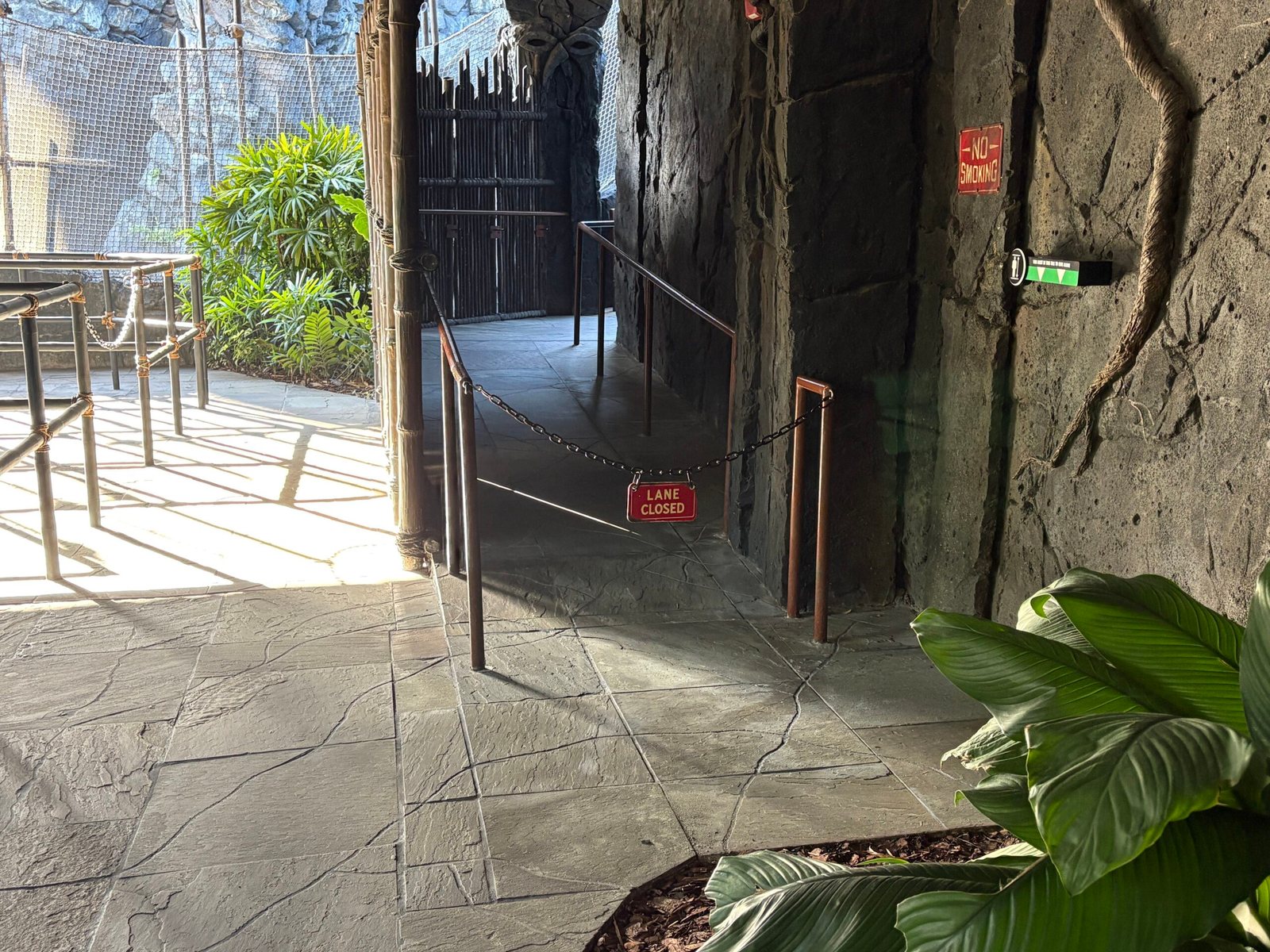 A chain with a red LANE CLOSED sign hangs across a side path branching off the rocky Skull Island queue