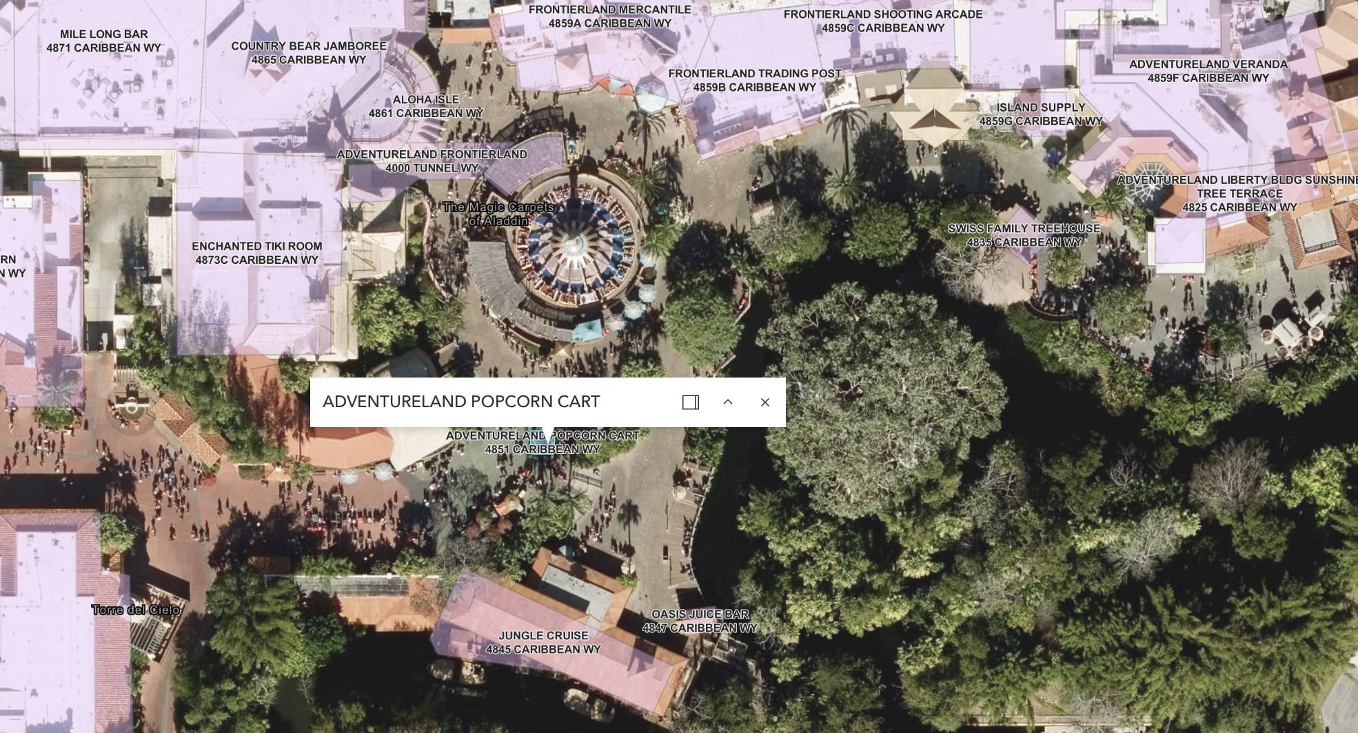 An aerial property map of central Adventureland with pink building outlines and address labels, a pin marked Adventureland Popcorn Cart at 4851 Caribbean Way on the walkway below the round Magic Carpets of Aladdin ride, Jungle Cruise at 4845 Caribbean Way further down, and the Enchanted Tiki Room at 4873C Caribbean Way to the upper left