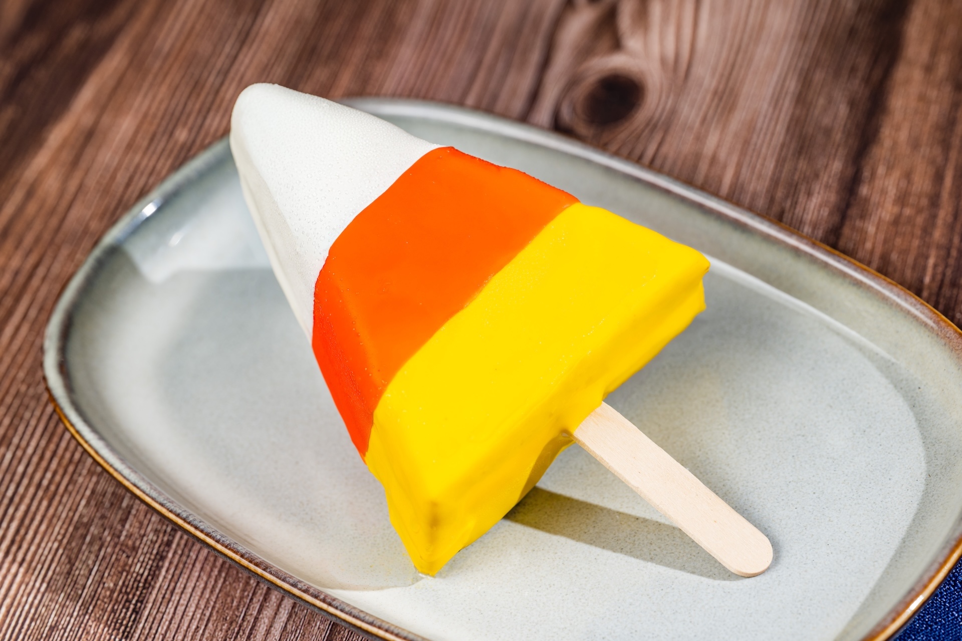 Candy Corn Pop, a cheesecake pop coated in white chocolate on a stick