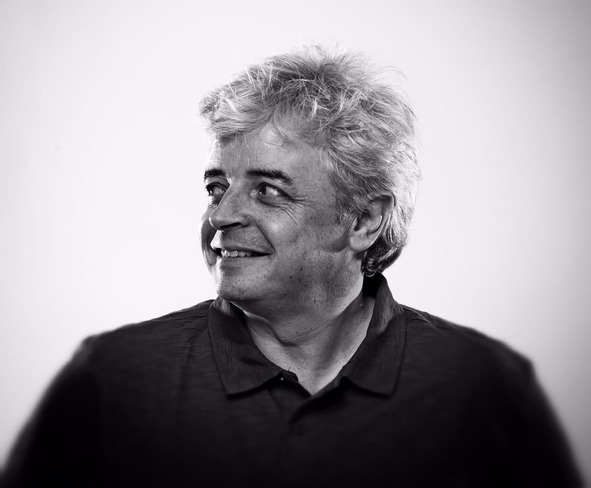 Black and white portrait of Paul Nolan, smiling and looking off to the side, wearing a dark polo shirt