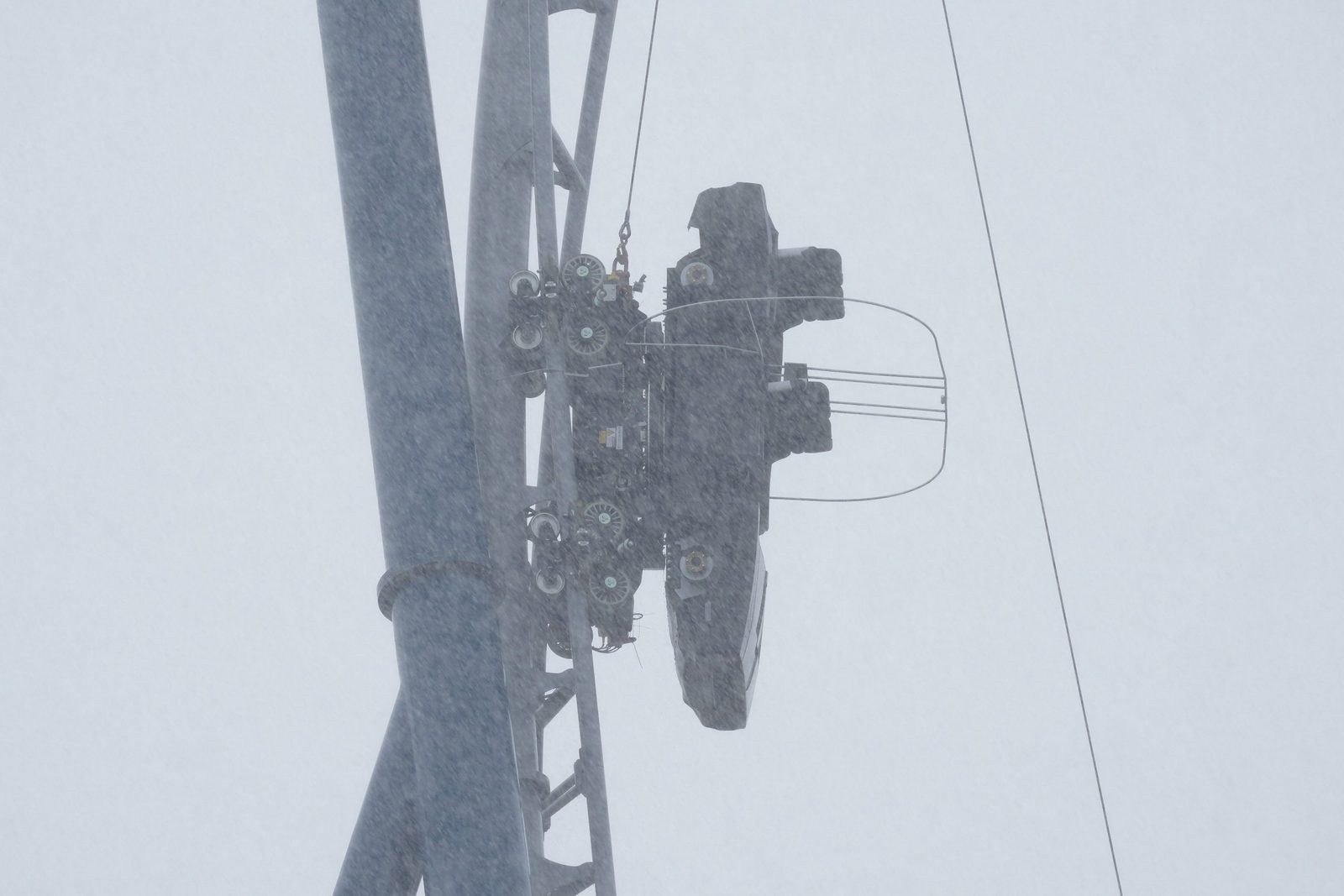 The test vehicle on the vertical spike seen through a gray haze of rain, with a wire rope running up the track