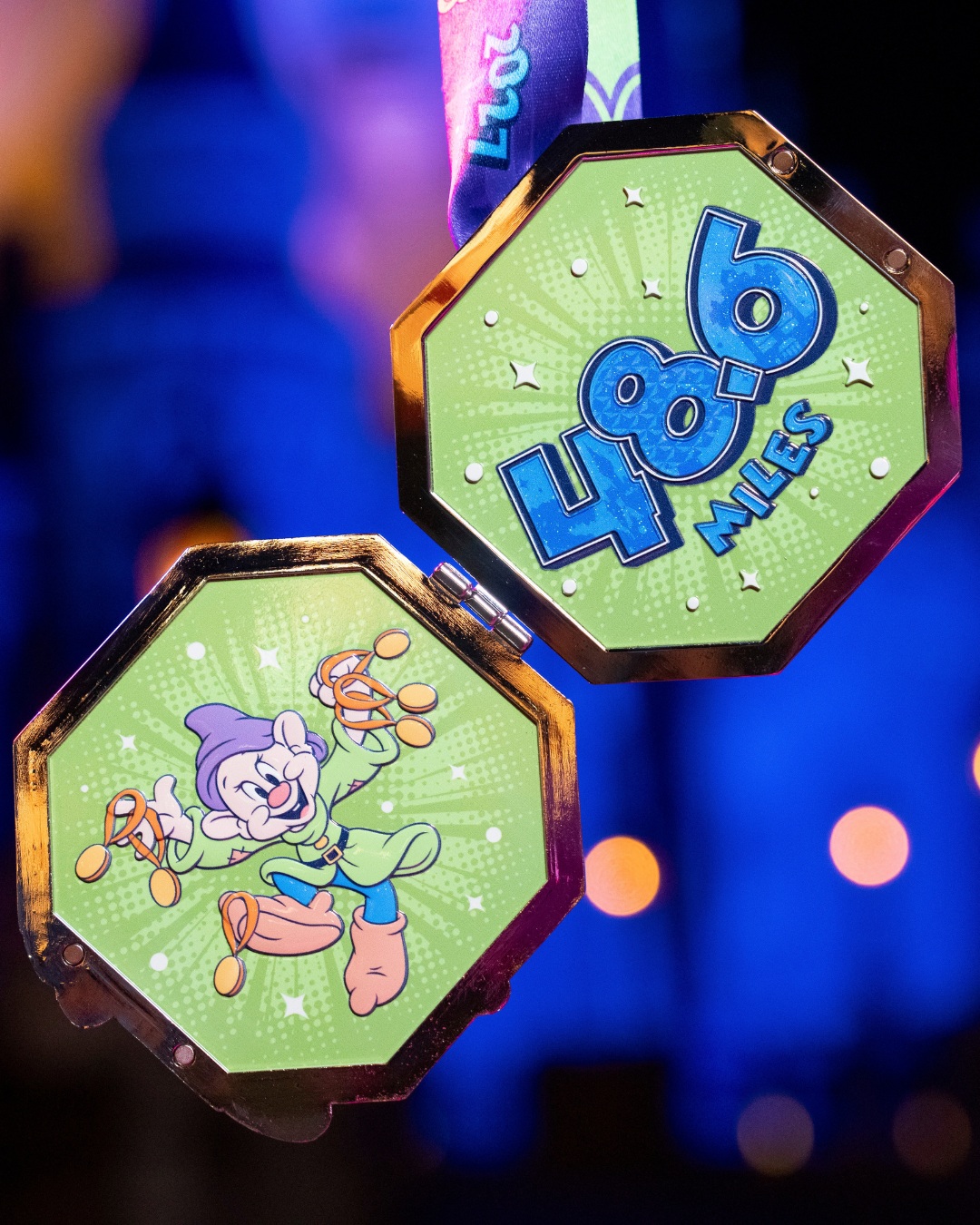 The Dopey Challenge medal opened like a locket, showing two green octagonal panels: one with Dopey in a green tunic and purple hat holding several gold medals on orange ribbons, the other with 48.6 Miles in glittering blue numerals
