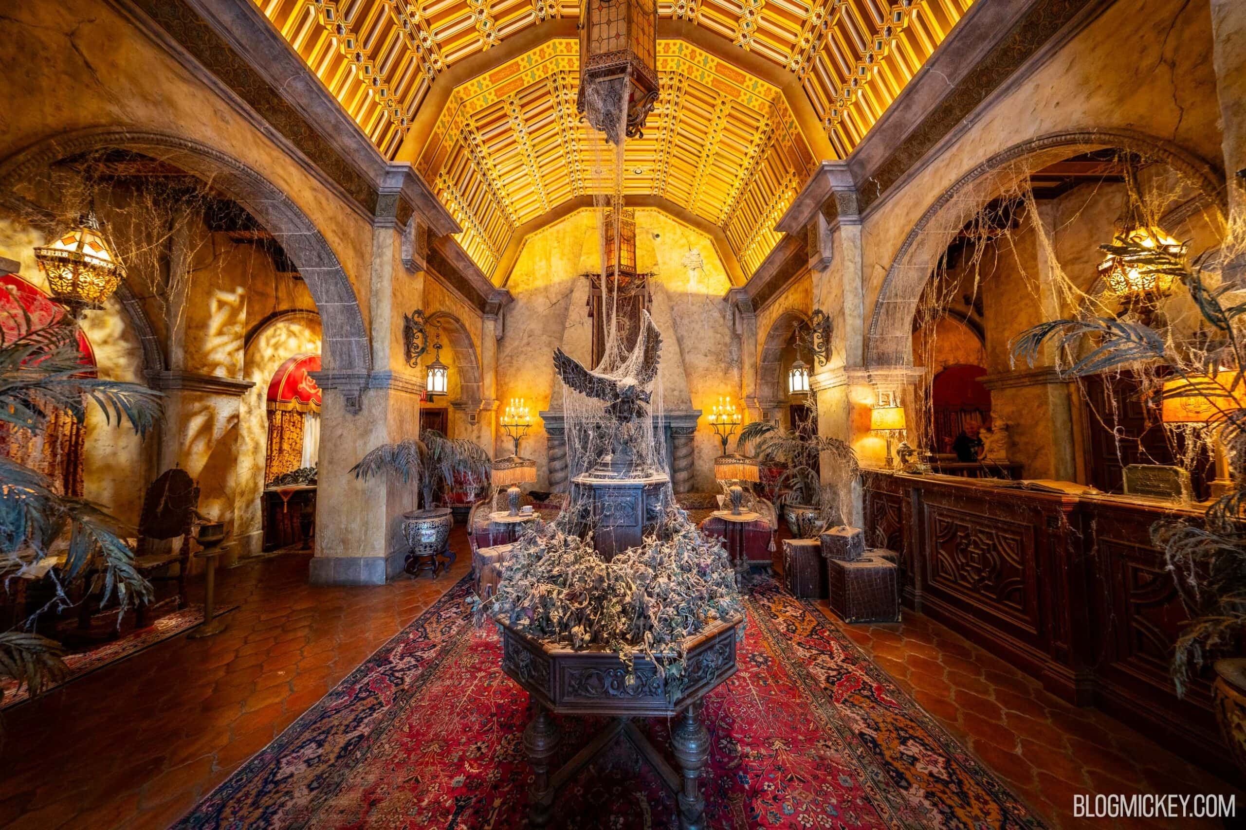 The cobweb-covered Hollywood Tower Hotel lobby with a gilded ceiling, a dusty eagle statue on a center planter of dead flowers, and the front desk on the right