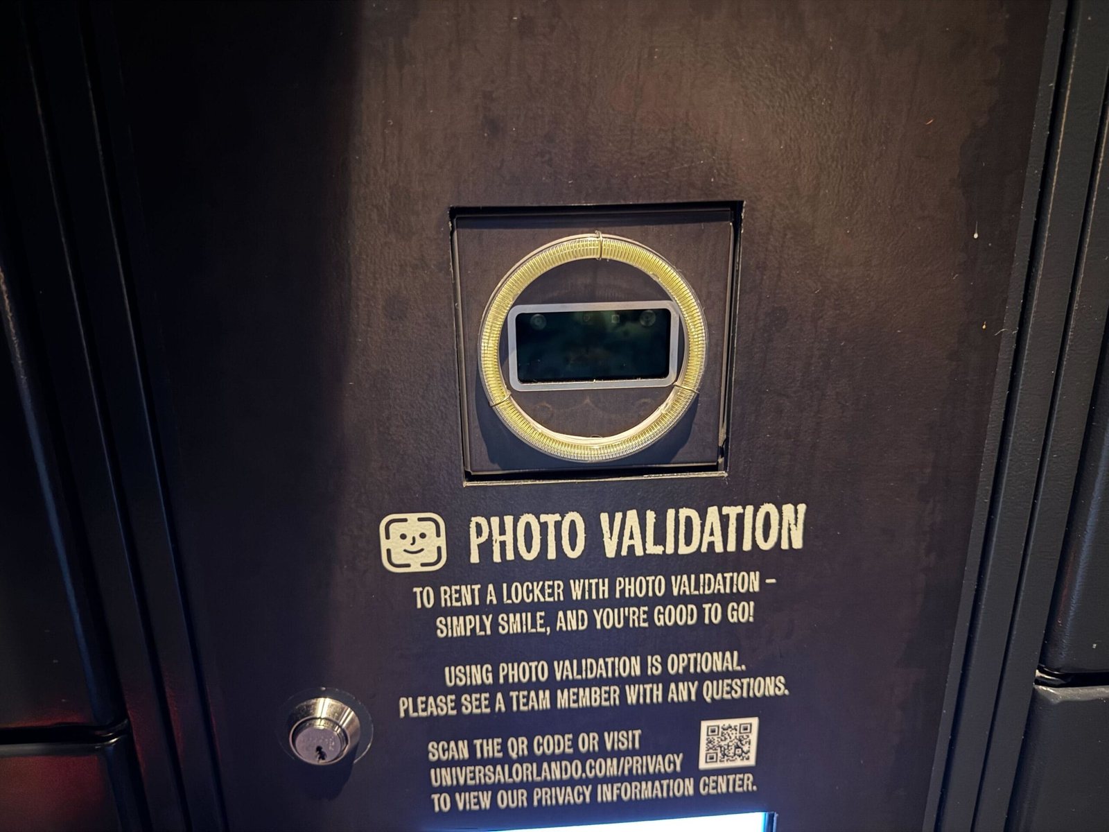 A dark locker panel with a ring light around a camera and a Photo Validation instruction plate with a QR code