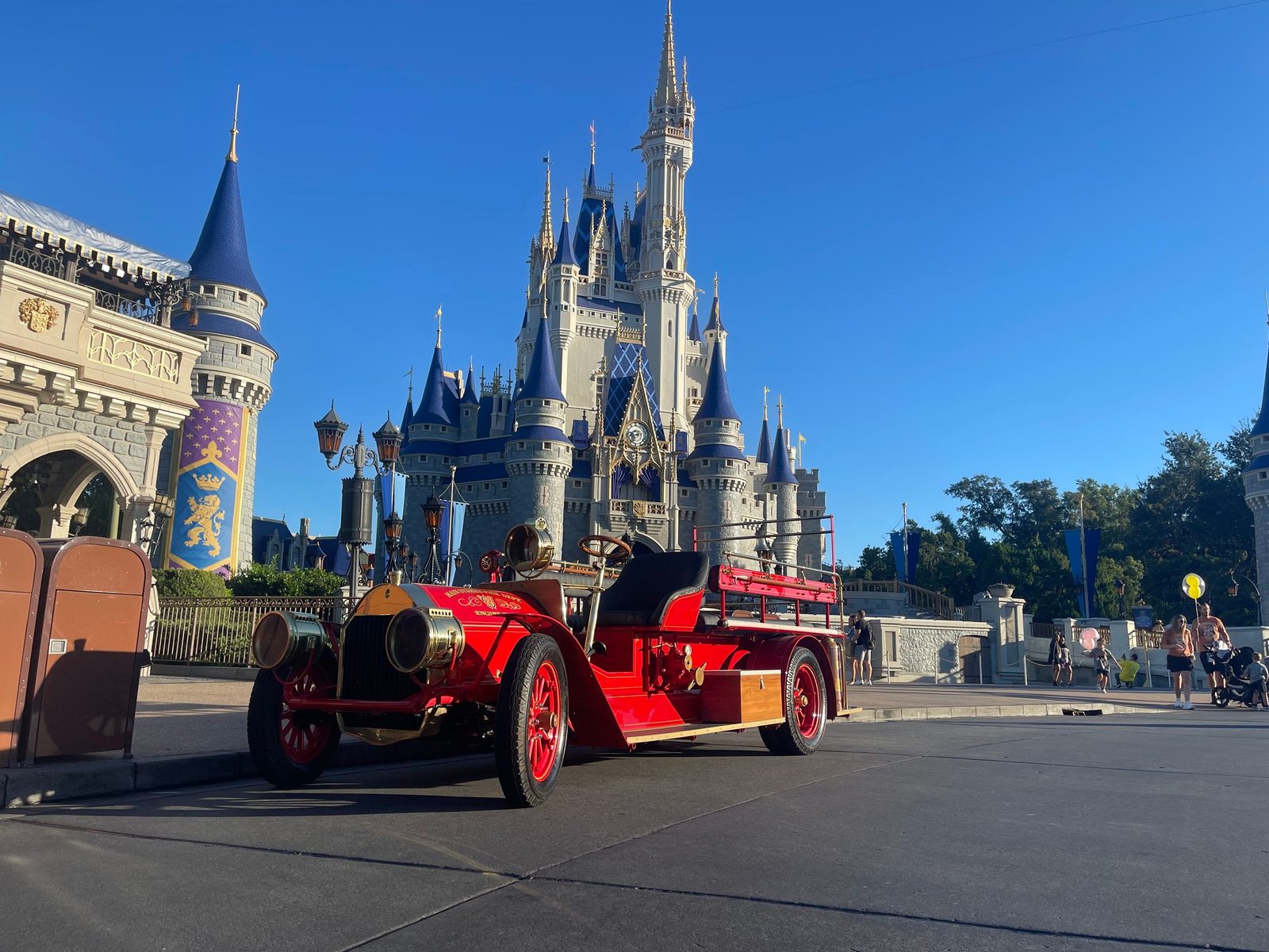 The red fire engine parked on the hub in front of Cinderella Castle under a clear blue sky