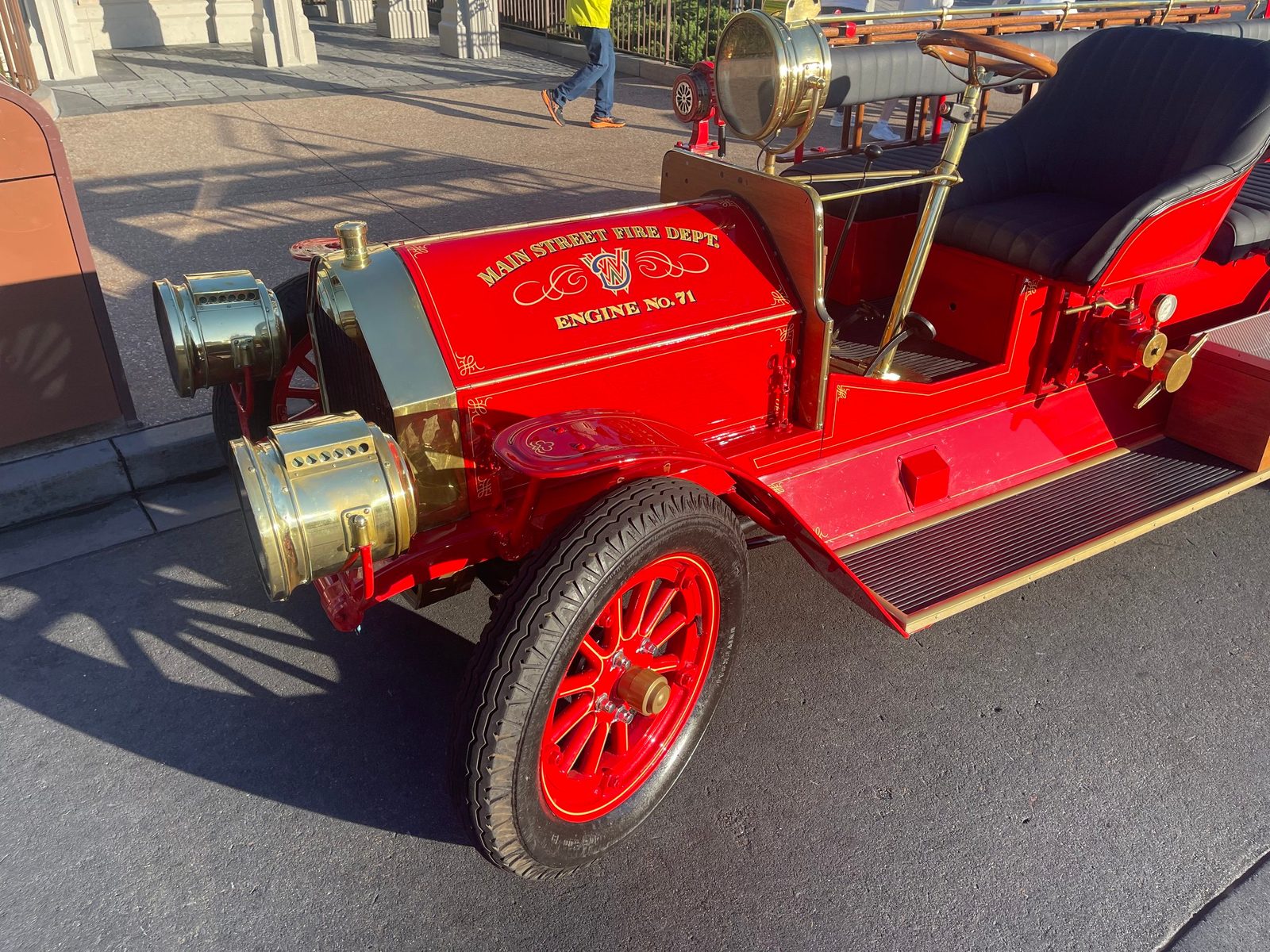 A close-up of the red hood of the fire engine, lettered Main Street Fire Dept. and Engine No. 71 in gold, with brass lamps and a red-spoked front wheel