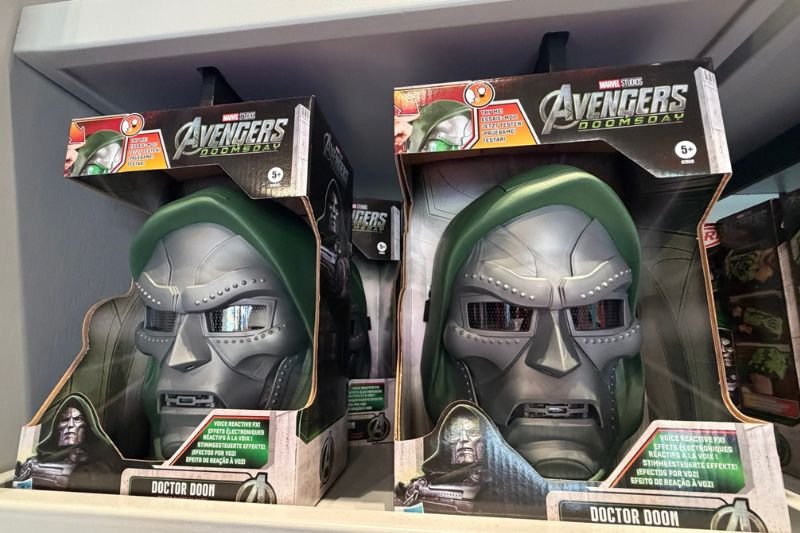 Two boxed Doctor Doom masks on a store shelf, each a silver metal face with a green hood, in Marvel Studios Avengers Doomsday packaging labeled Doctor Doom