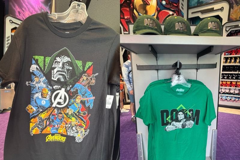 Two shirts on display in a Marvel store: a black T-shirt with Doctor Doom above Marvel heroes around an Avengers logo, and a green T-shirt reading DOOM with Doctor Doom artwork, beside a shelf of green caps