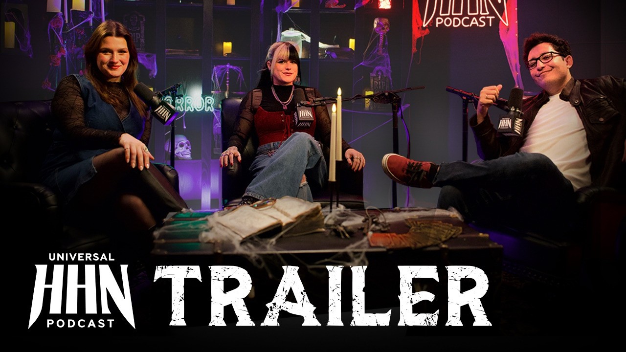 Three podcast hosts with microphones sitting in black leather chairs on a dim, cobwebbed set with candles, skulls and a neon HHN Podcast sign, above the Universal HHN Podcast logo and the word TRAILER